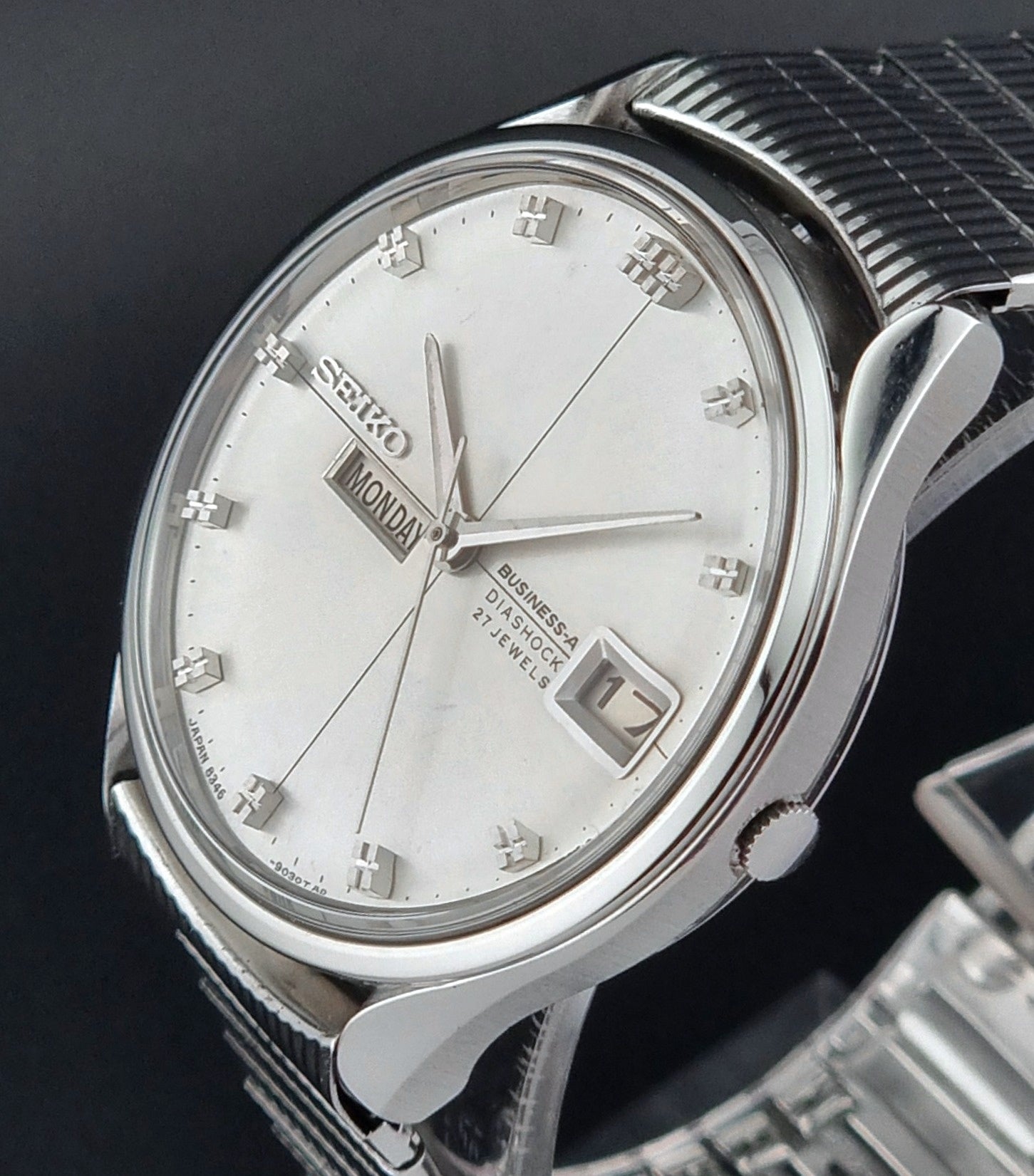 Seiko watch with silver case and white face on a dark background