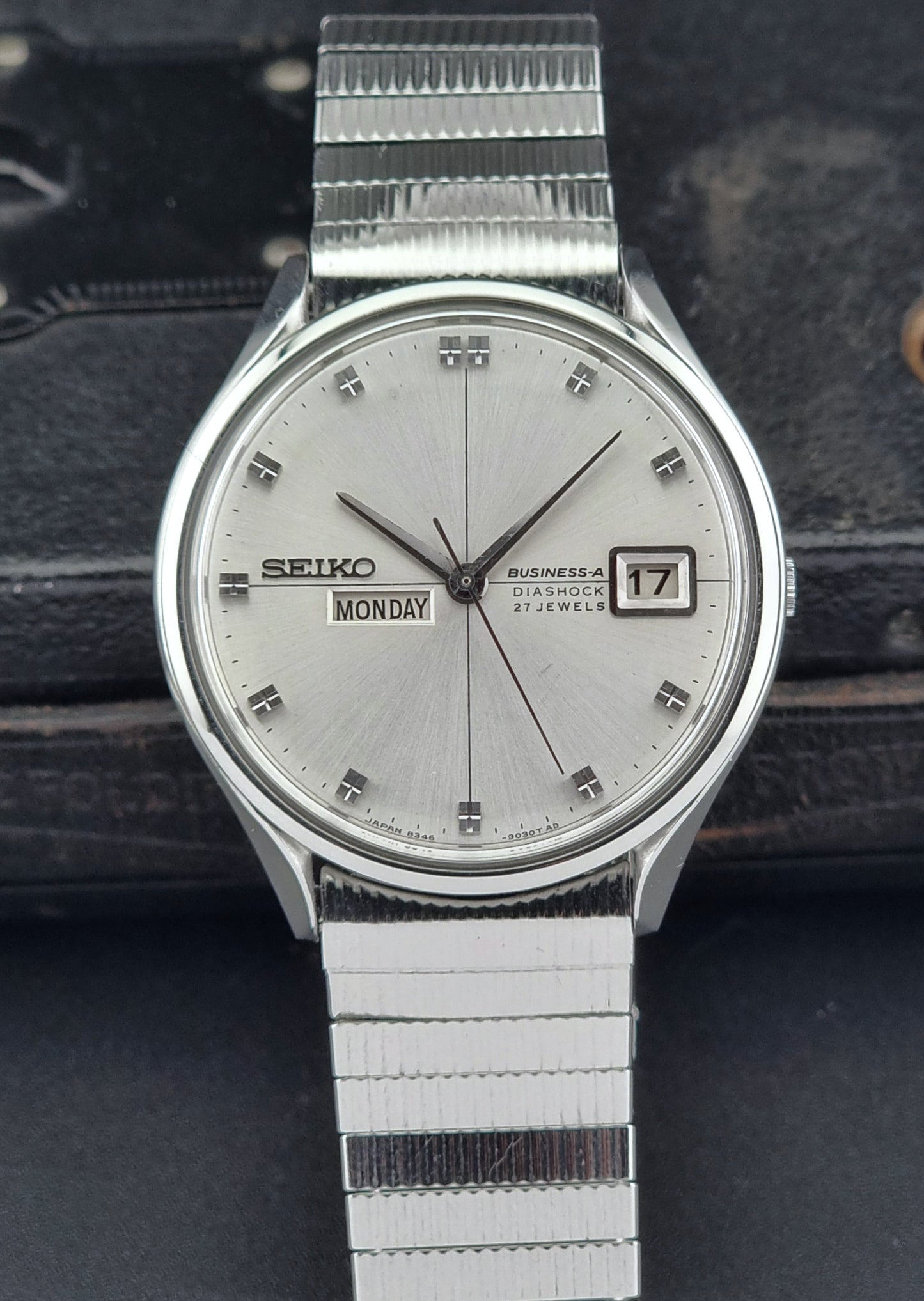 Silver Seiko watch with a white face on a dark textured background
