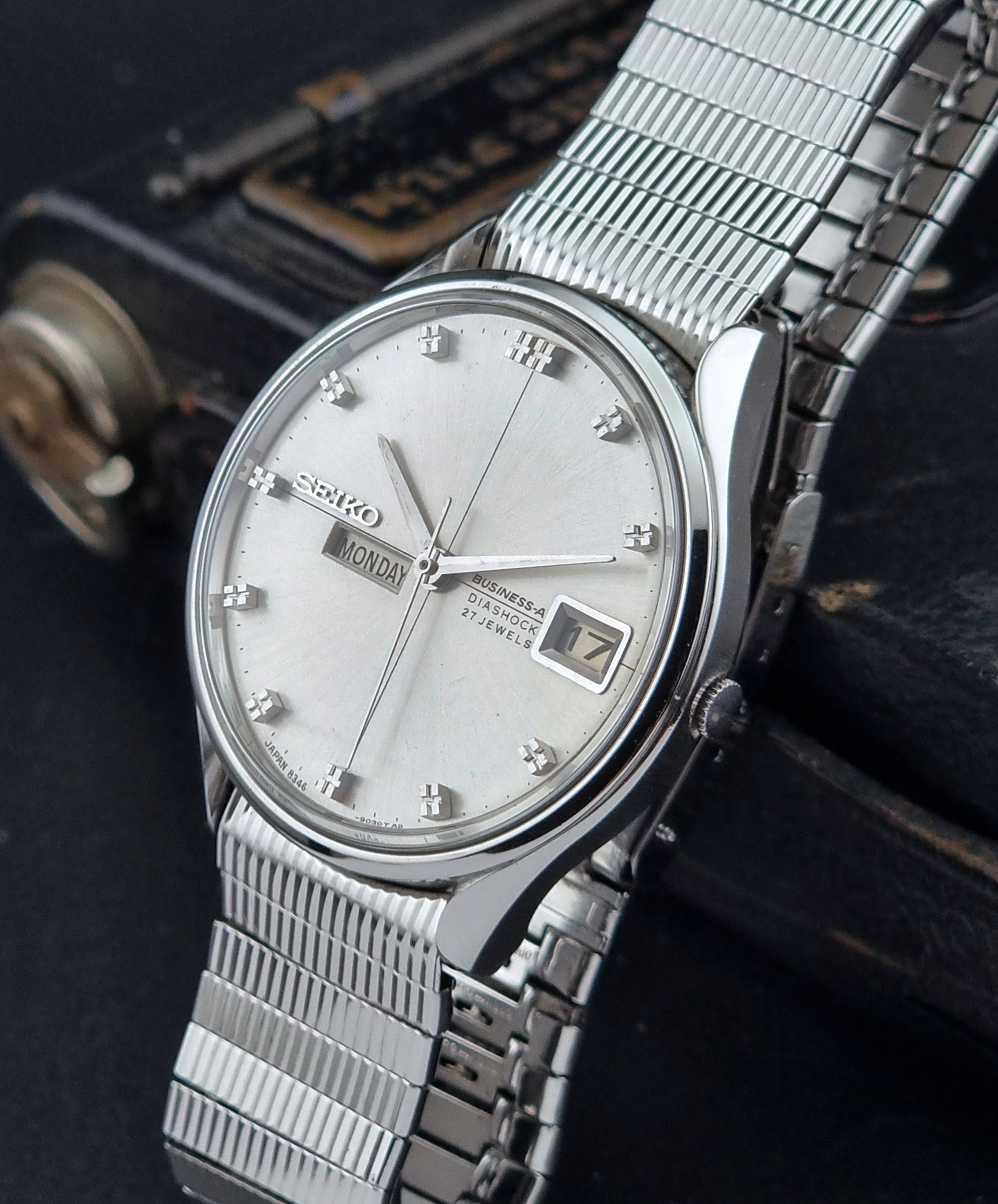 Silver Seiko watch with a mesh band on a dark background