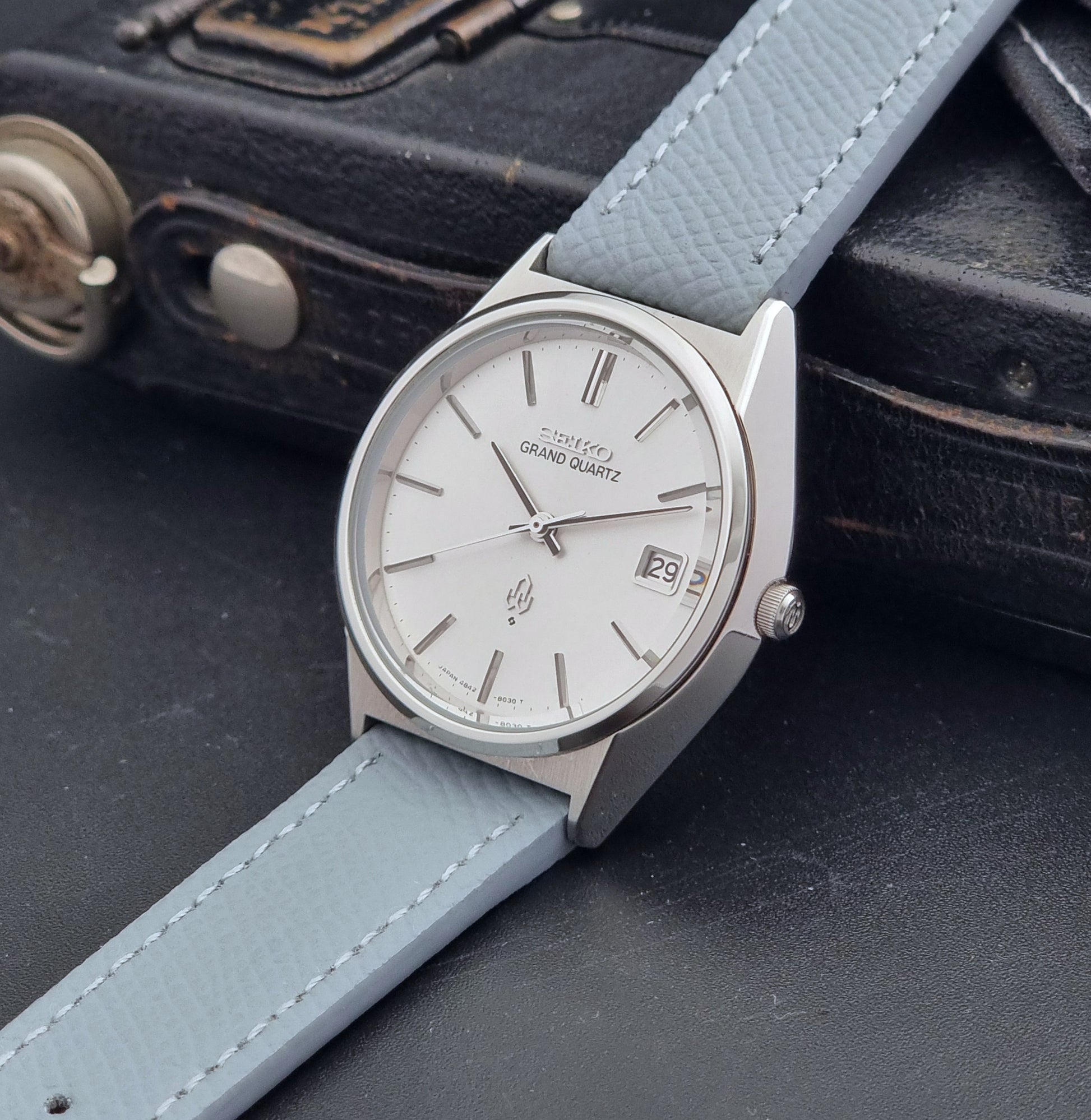Vintage Seiko Grand Quartz watch 4842-8041 with light grey strap and silver case on a dark gray background crown view