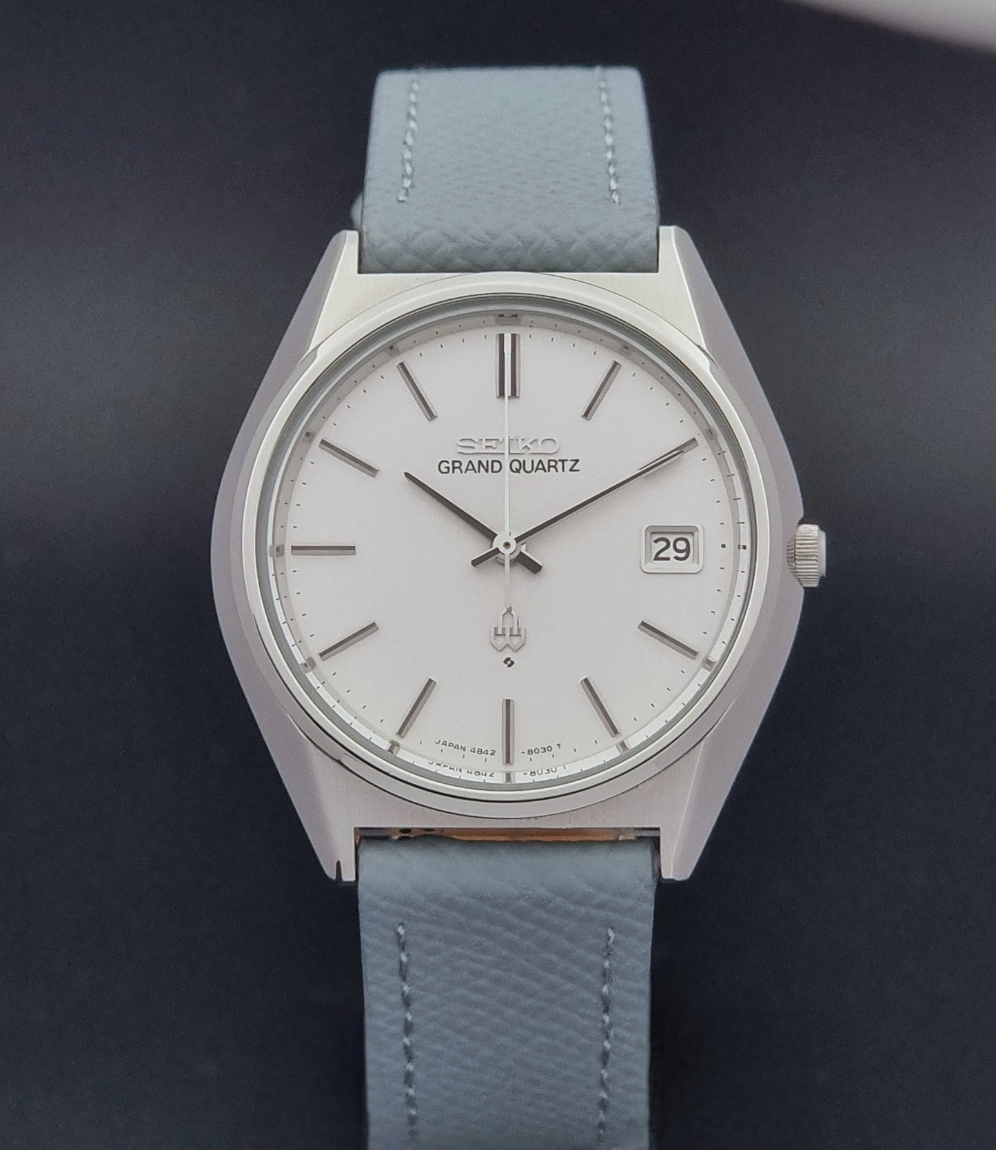 Vintage Seiko Grand Quartz watch 4842-8041 with light grey strap and silver case on a dark gray background close dial view