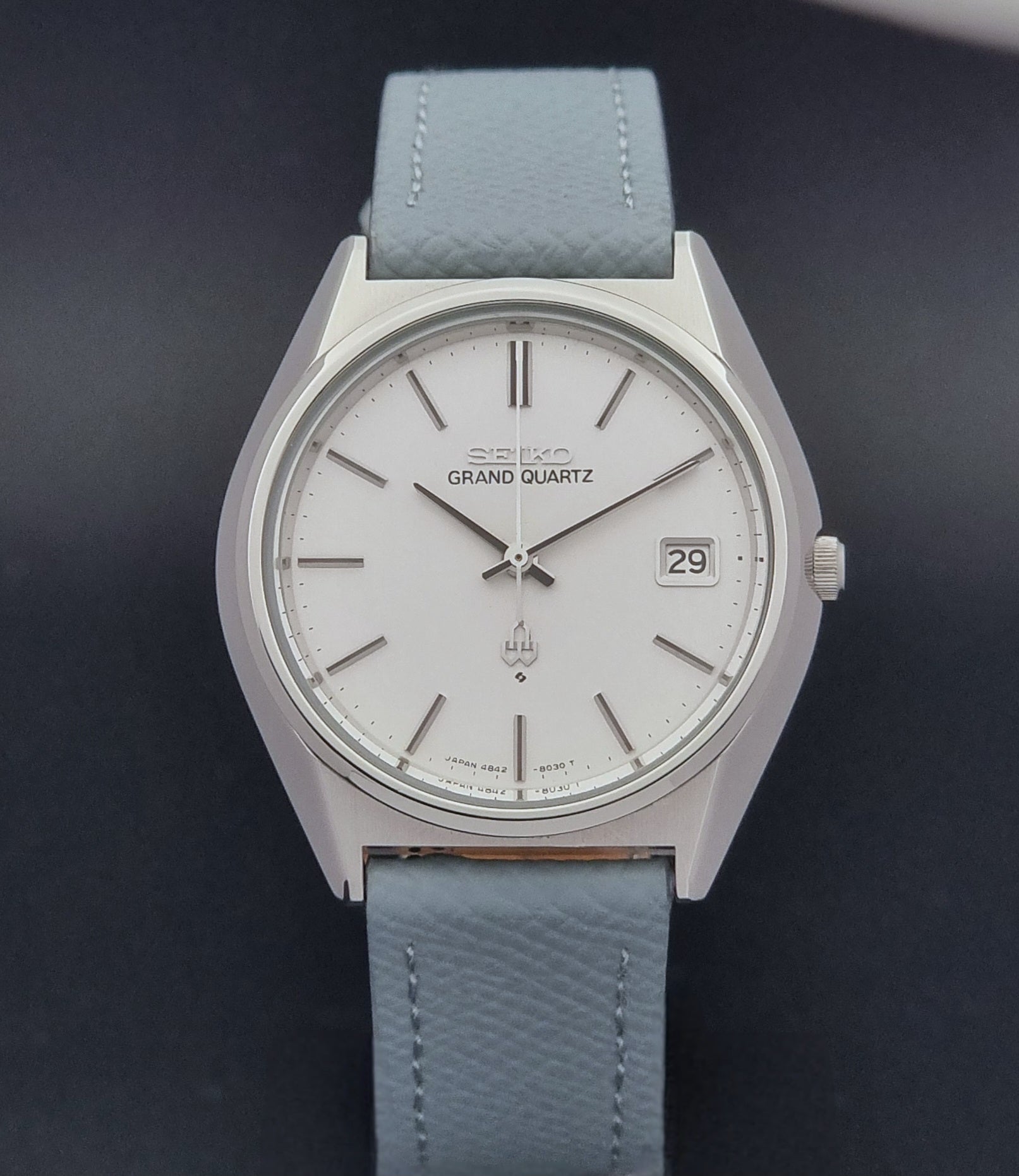 Vintage Seiko Grand Quartz watch 4842-8041 with light grey strap and silver case on a dark gray background close dial view