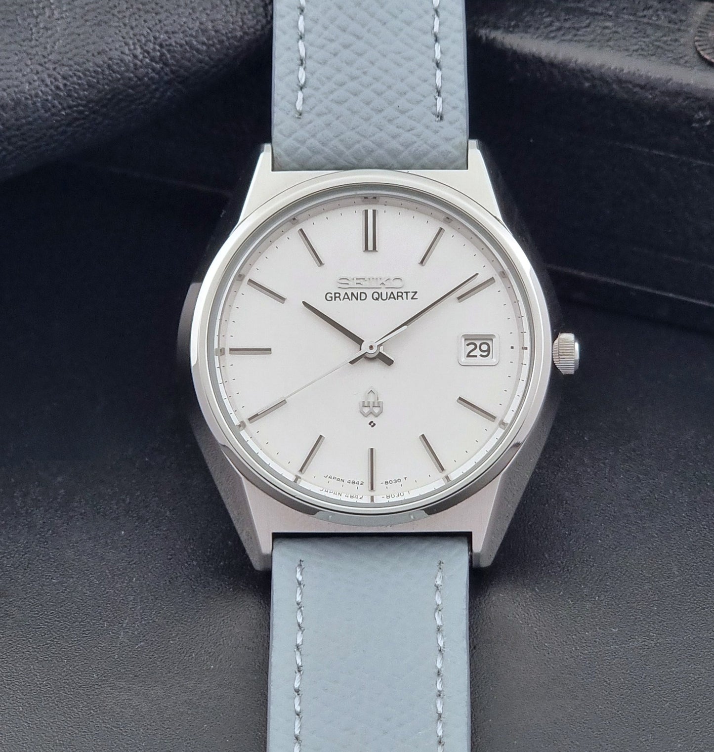 Vintage Seiko Grand Quartz watch 4842-8041 with light grey strap and silver case on a dark gray background dial view