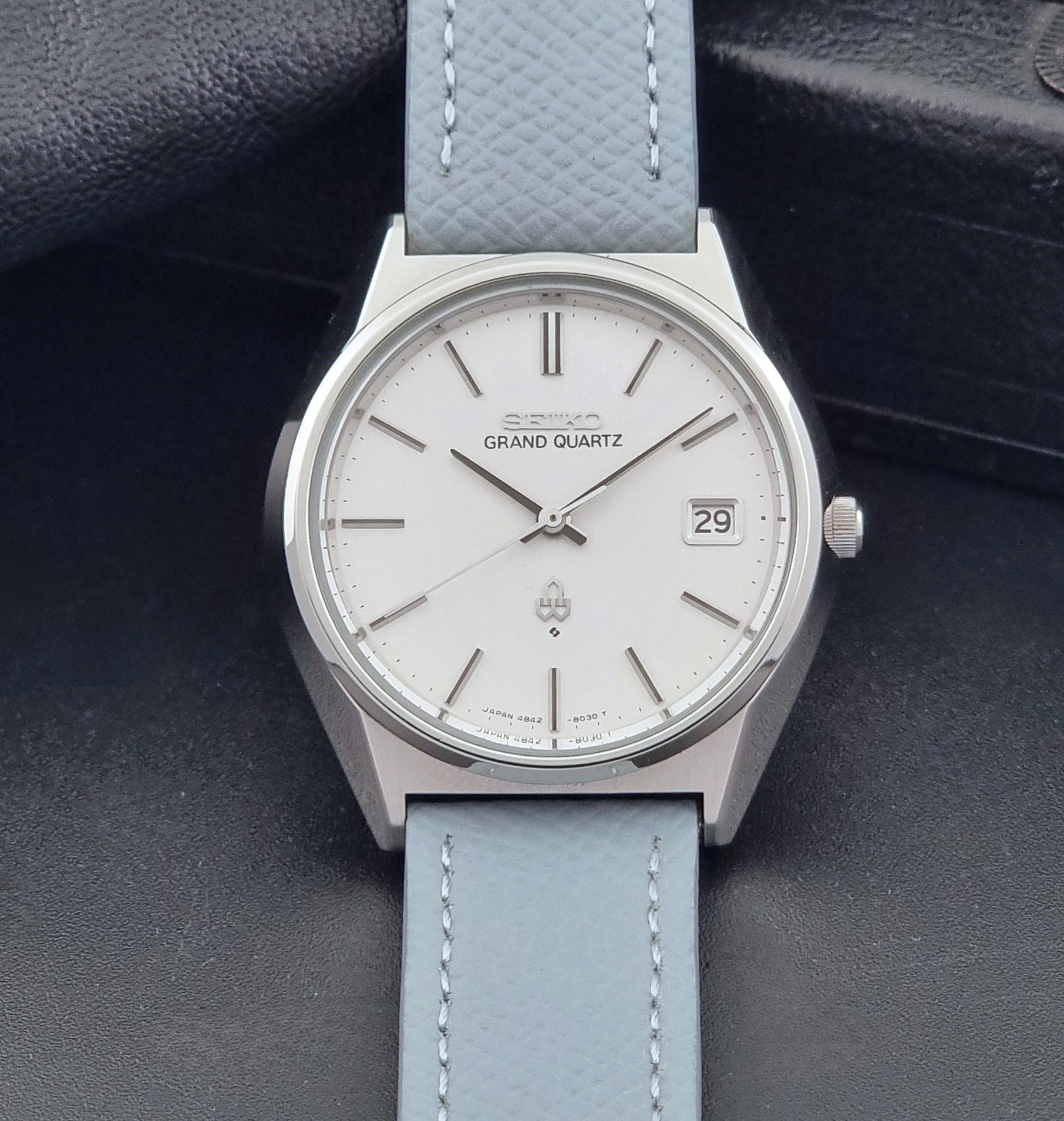 Vintage Seiko Grand Quartz watch 4842-8041 with light grey strap and silver case on a dark gray background dial view