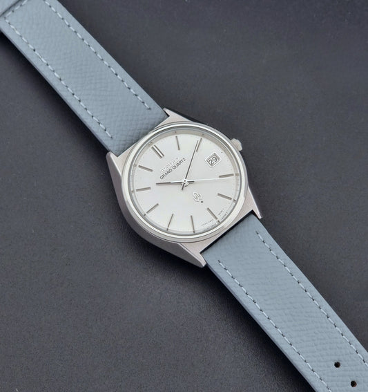 Vintage Seiko Grand Quartz watch 4842-8041 with light grey strap and silver case on a dark gray background dial