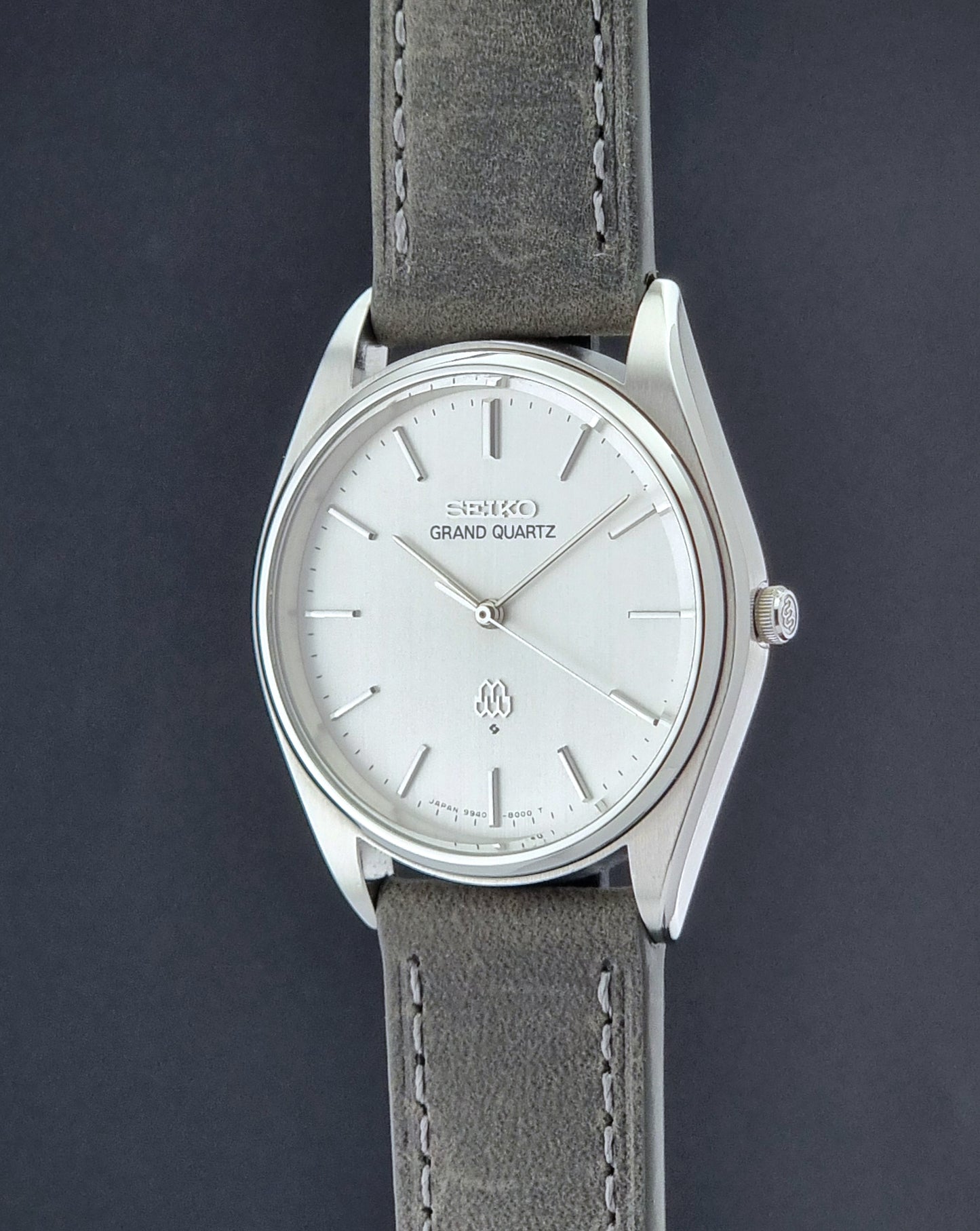 Vintage Seiko Grand Quartz 9940-8000 Watch with gray leather strap and white dial on a dark background crown profile view
