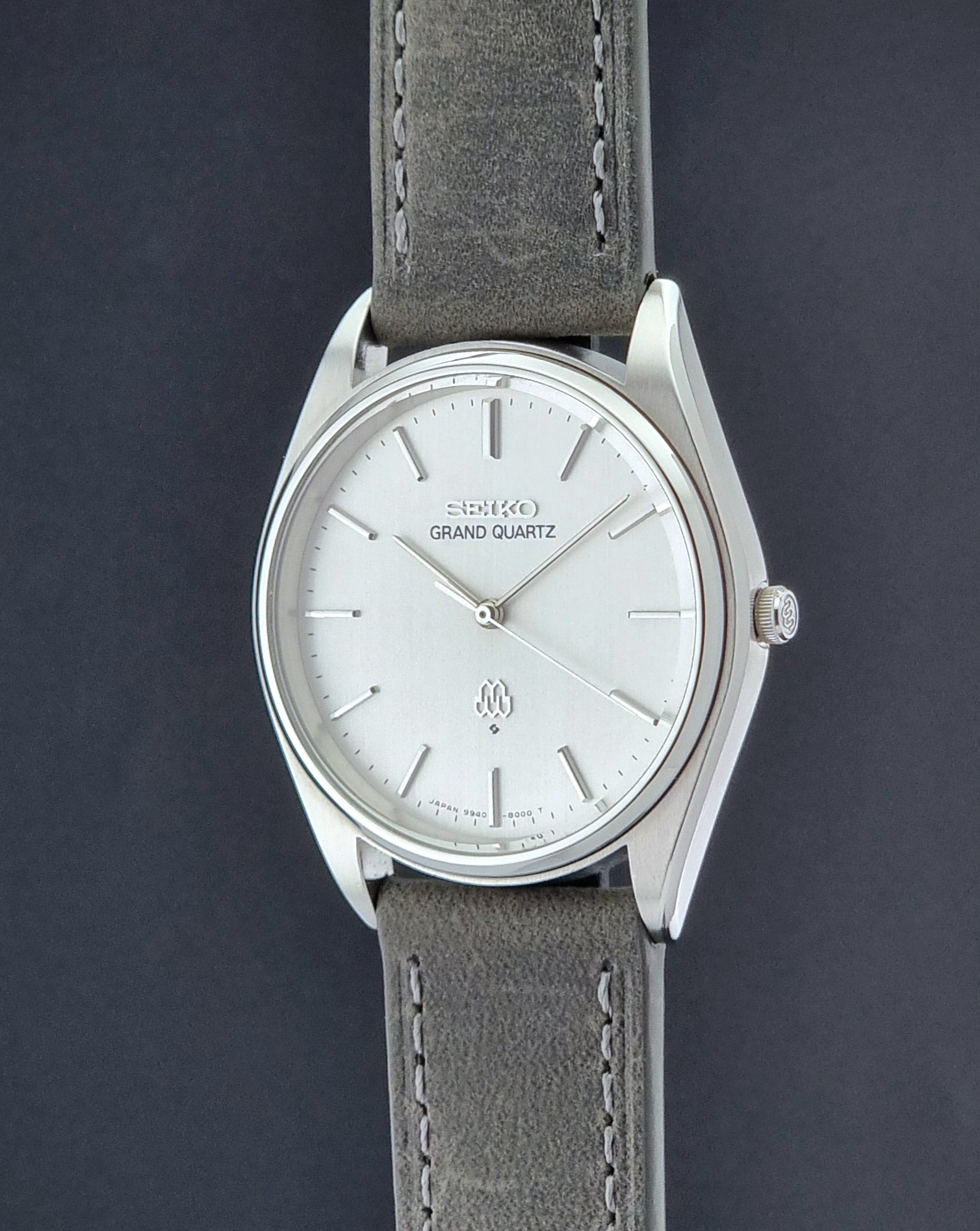 Vintage Seiko Grand Quartz 9940-8000 Watch with gray leather strap and white dial on a dark background crown profile view