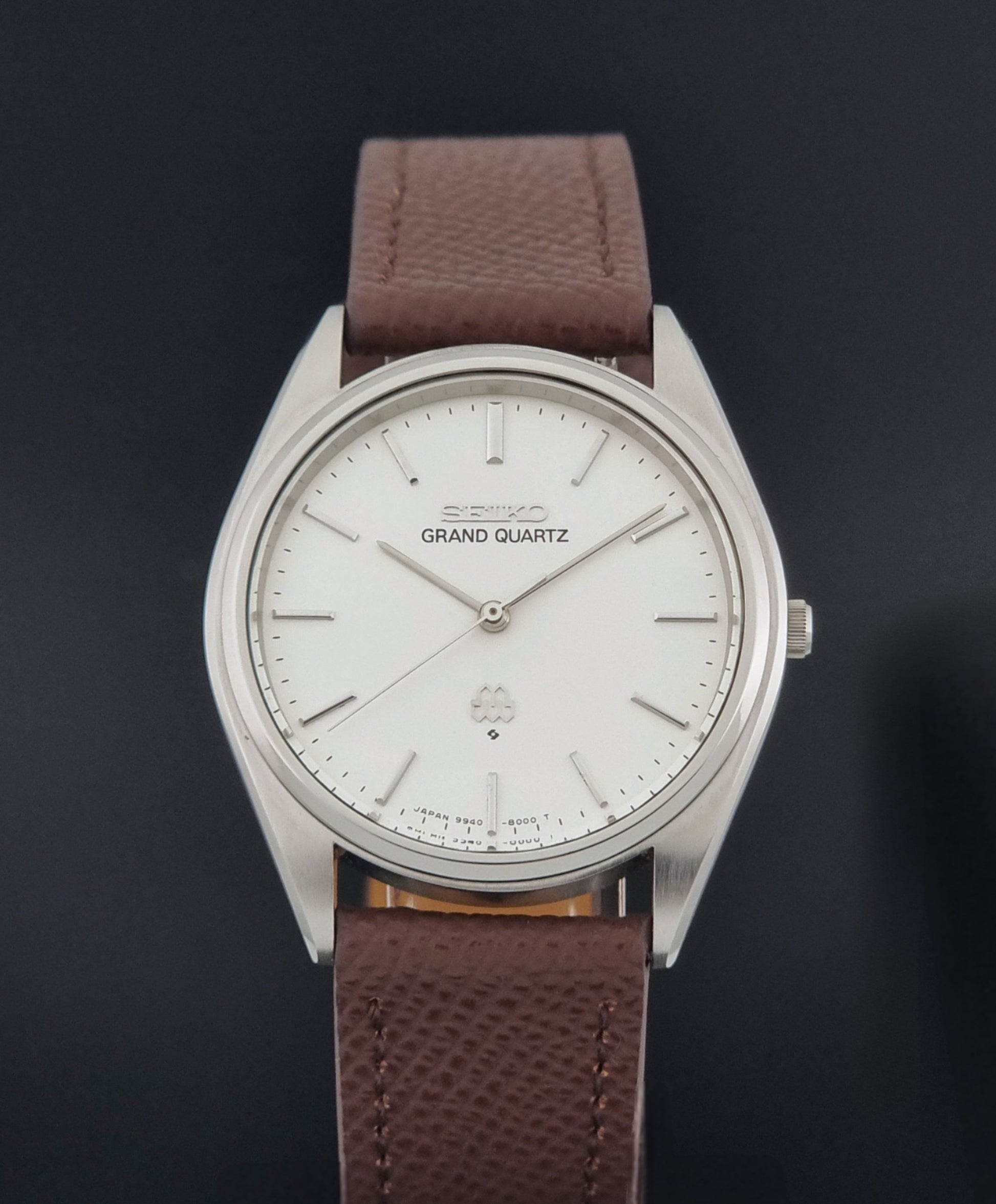 Vintage Seiko Grand Quartz 9940-8000 with a brown textured leather strap on a dark gray background close dial view