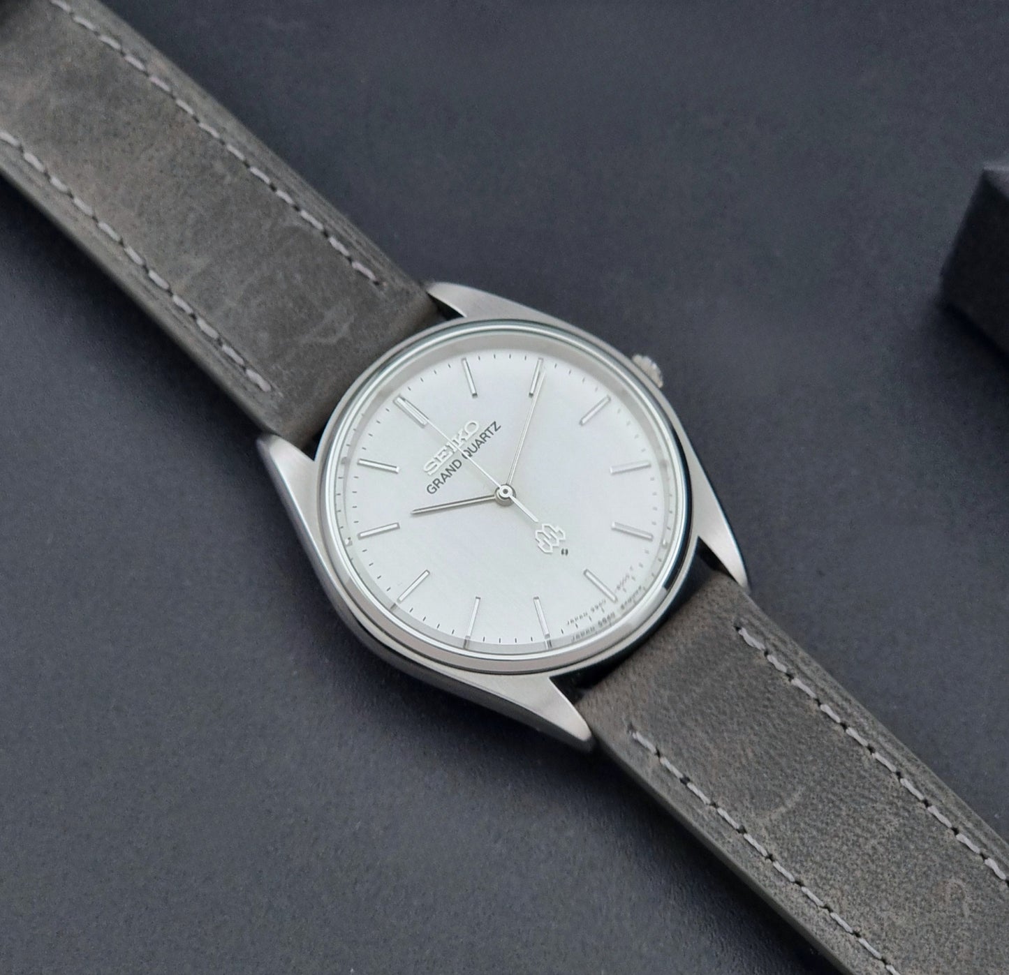 Vintage Seiko Grand Quartz 9940-8000 Watch with gray leather strap and white dial on a dark background dial
