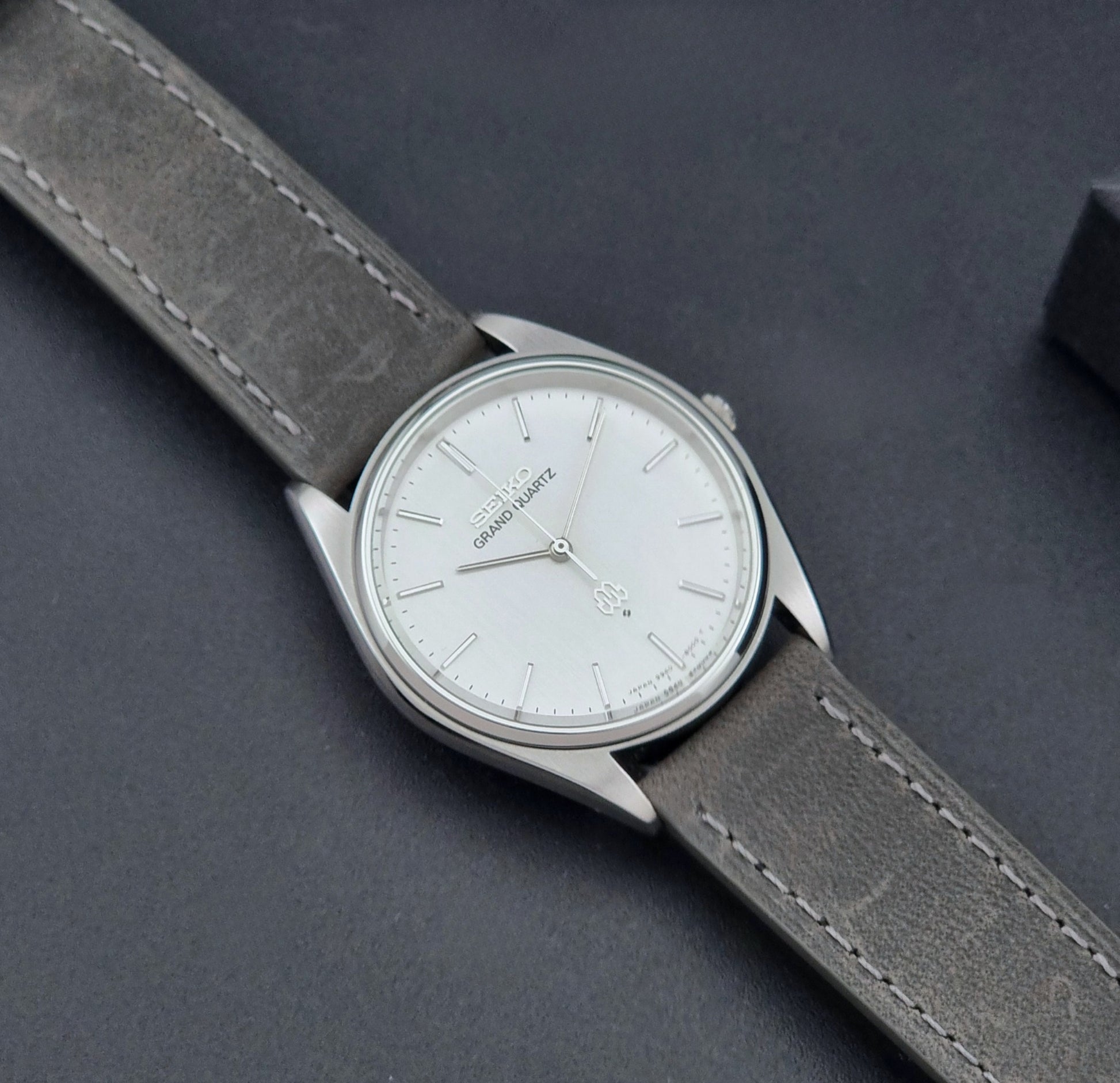 Vintage Seiko Grand Quartz 9940-8000 Watch with gray leather strap and white dial on a dark background dial