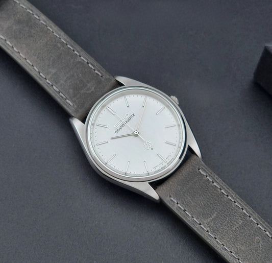 Vintage Seiko Grand Quartz 9940-8000 Watch with gray leather strap and white dial on a dark background dial