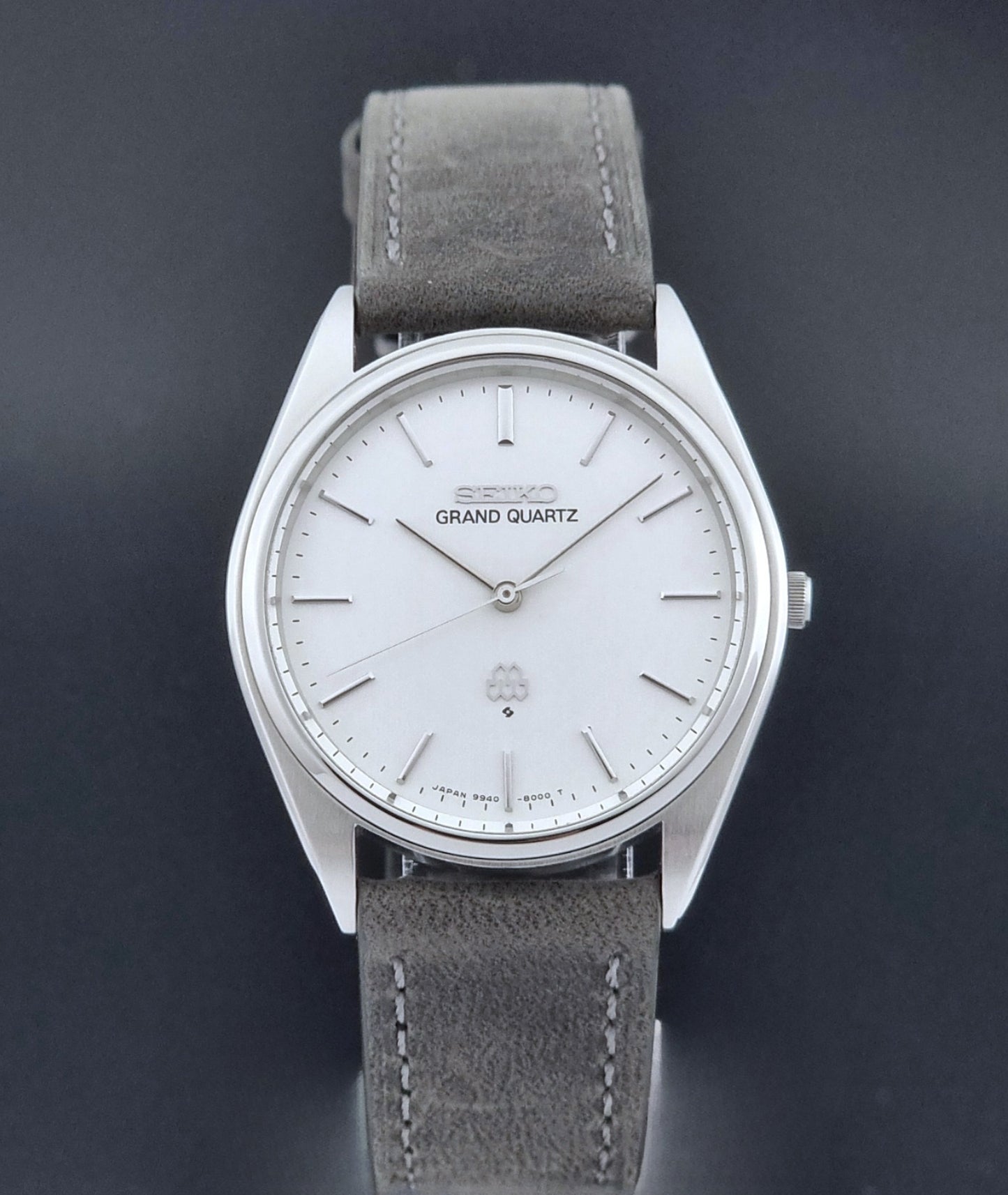 Vintage Seiko Grand Quartz 9940-8000 Watch with gray leather strap and white dial on a dark background close dial view