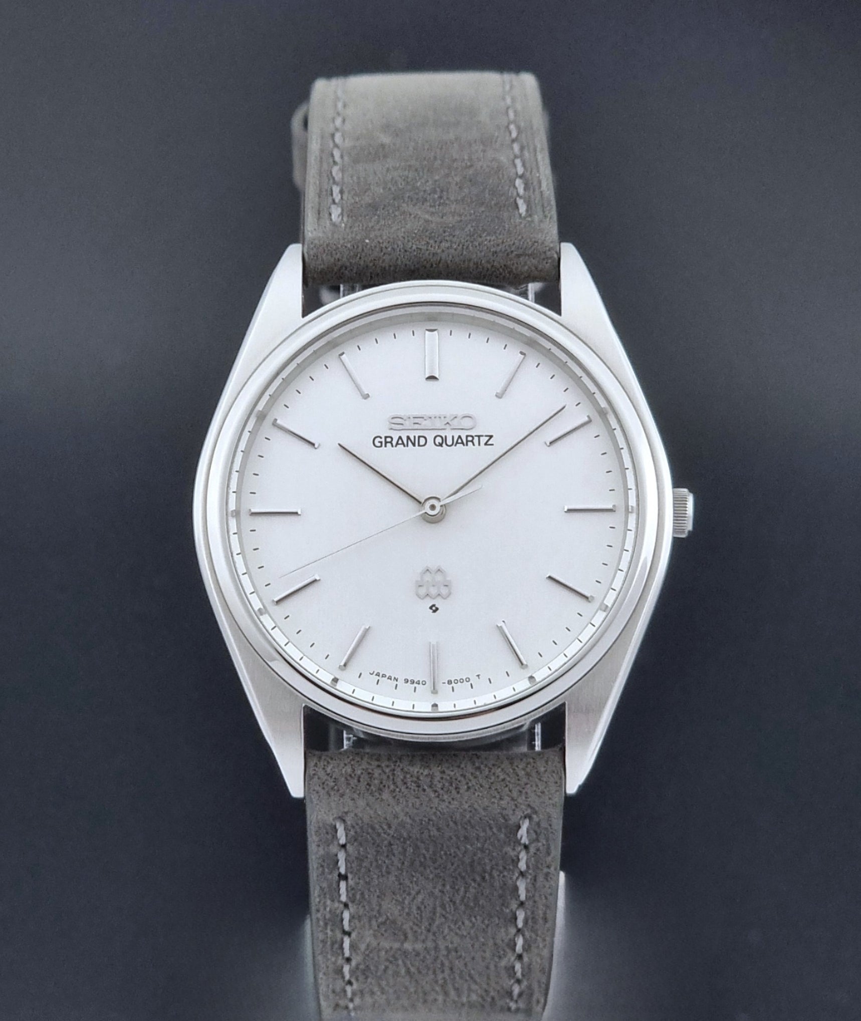 Vintage Seiko Grand Quartz 9940-8000 Watch with gray leather strap and white dial on a dark background close dial view
