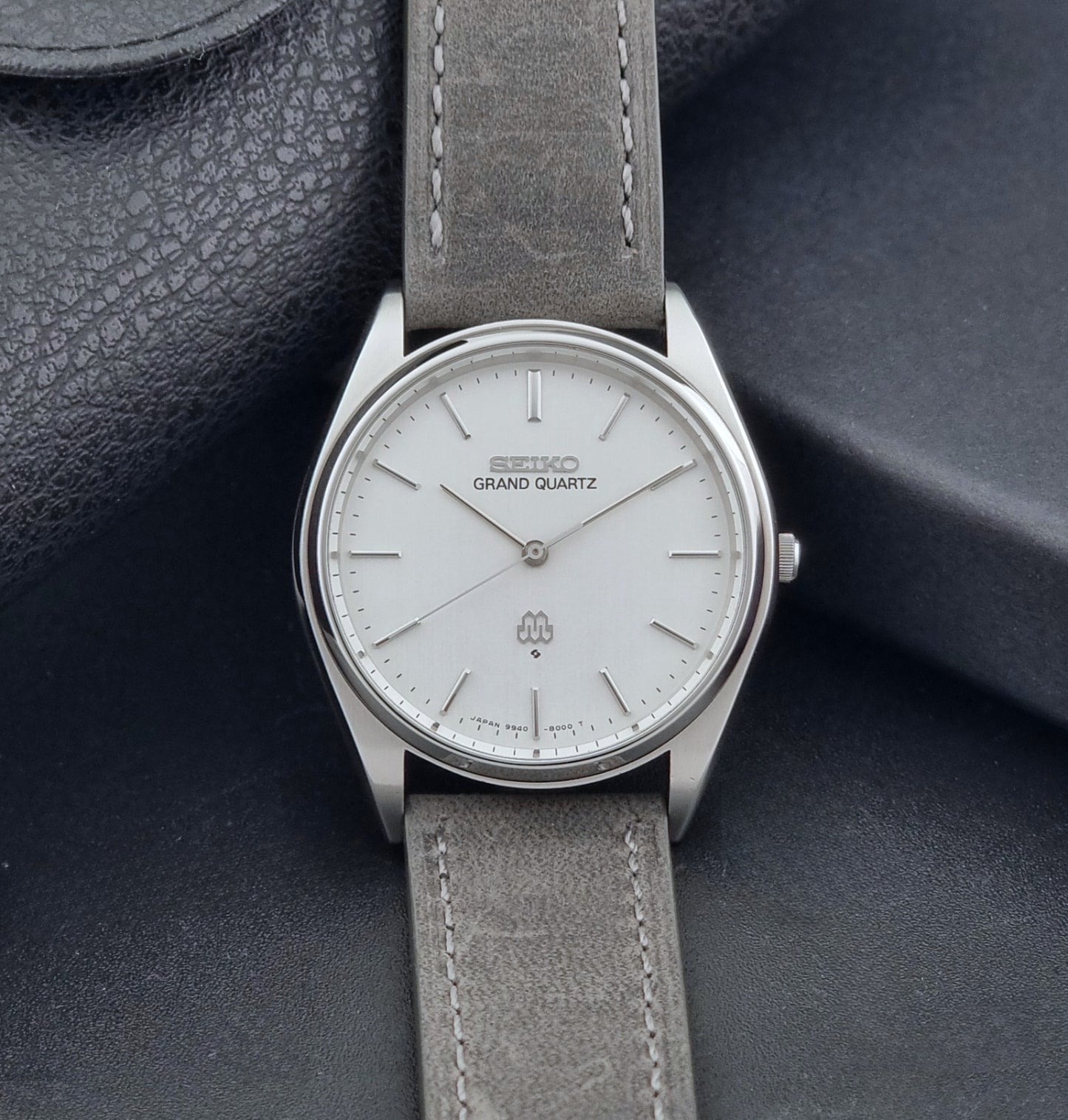 Vintage Seiko Grand Quartz 9940-8000 Watch with gray leather strap and white dial on a dark background dial view