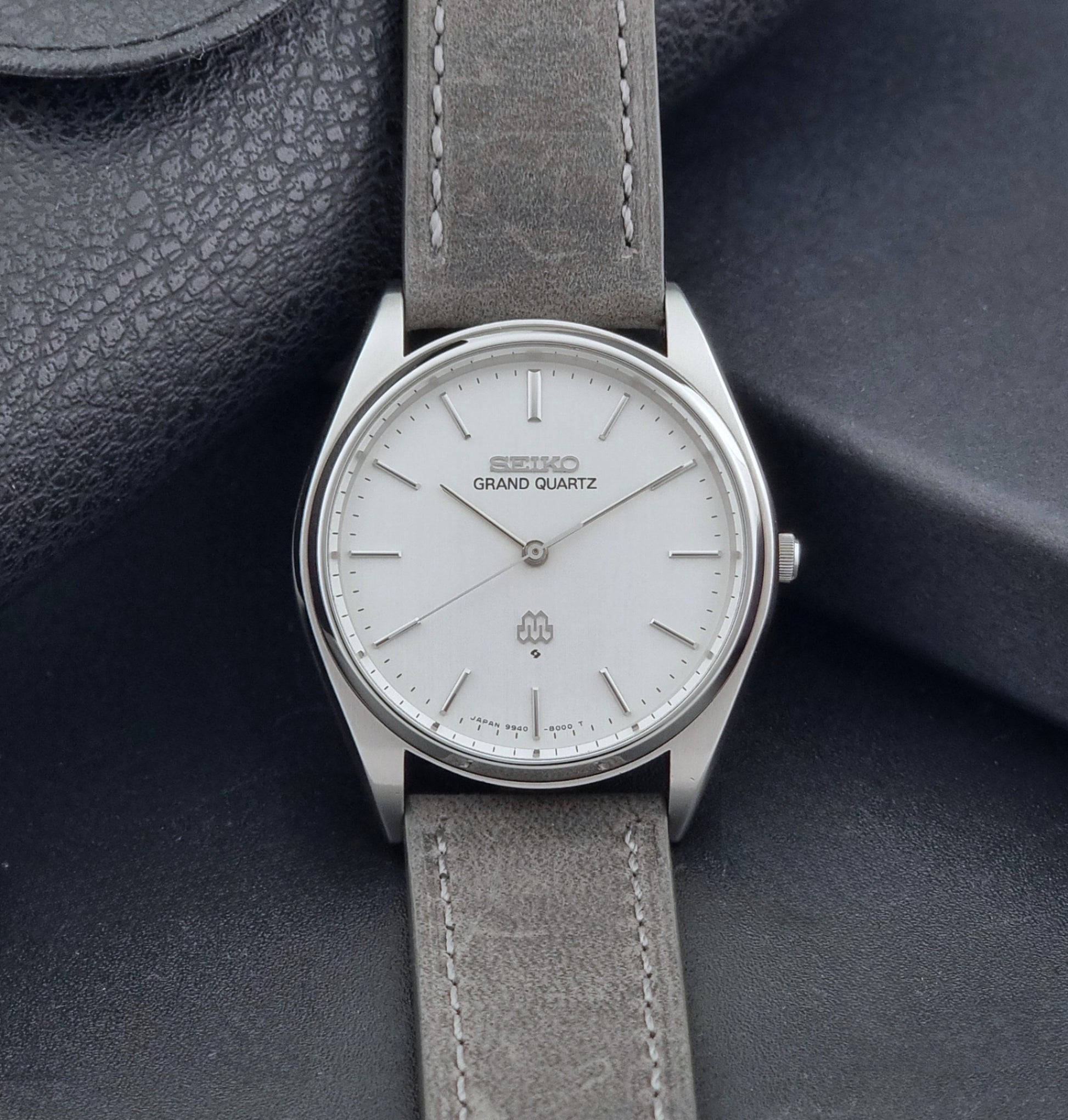 Vintage Seiko Grand Quartz 9940-8000 Watch with gray leather strap and white dial on a dark background dial view