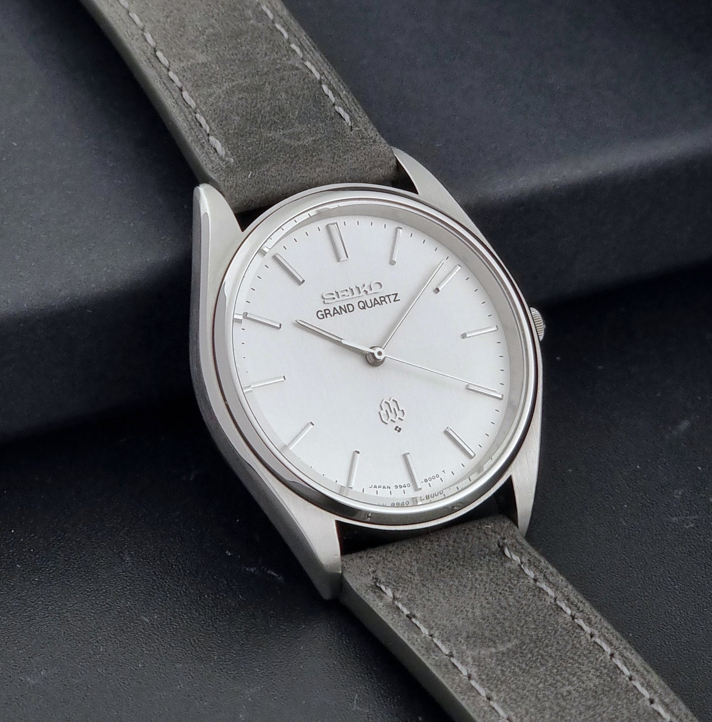 Vintage Seiko Grand Quartz 9940-8000 Watch with gray leather strap and white dial on a dark background side view