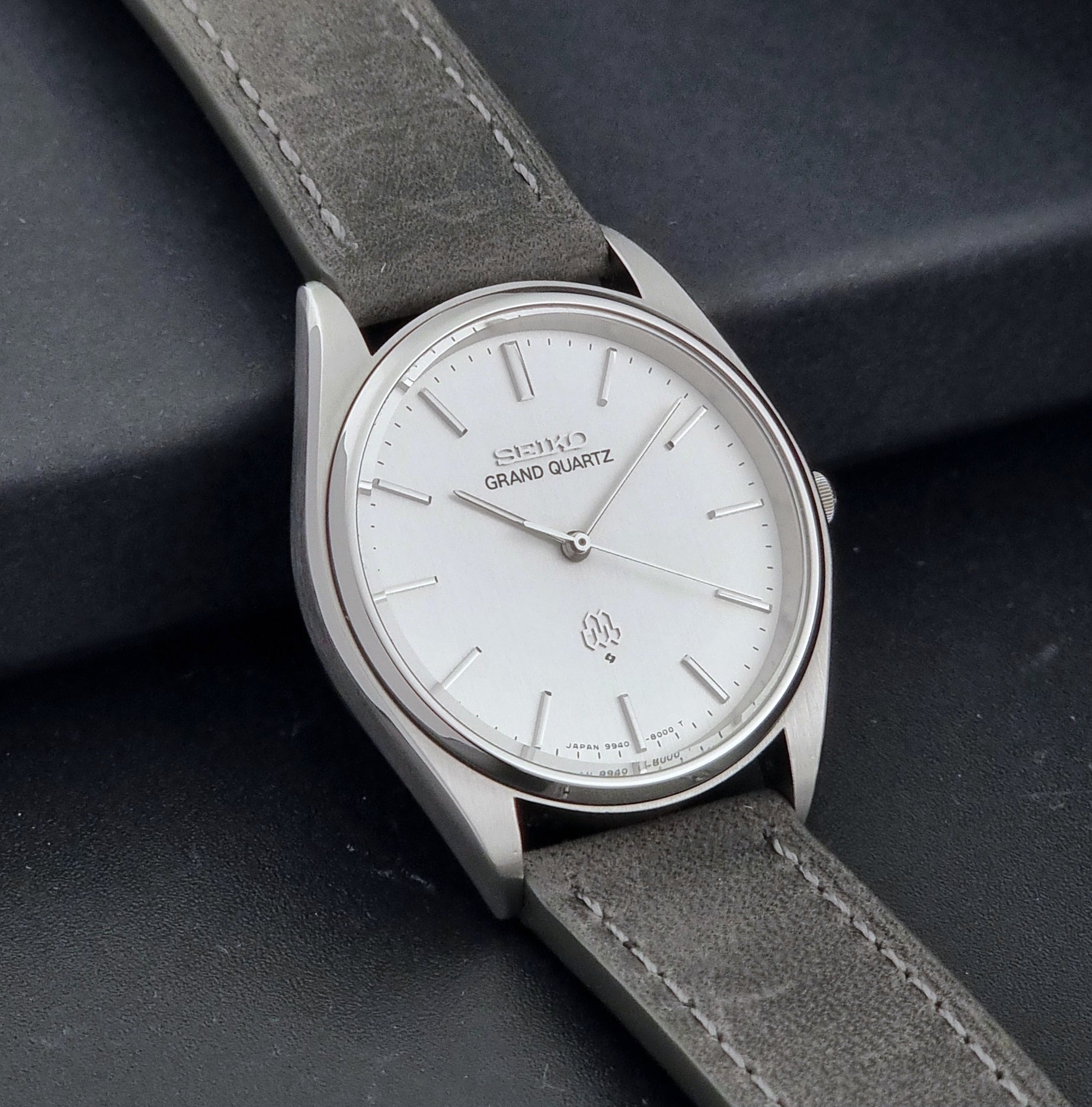 Vintage Seiko Grand Quartz 9940-8000 Watch with gray leather strap and white dial on a dark background side view