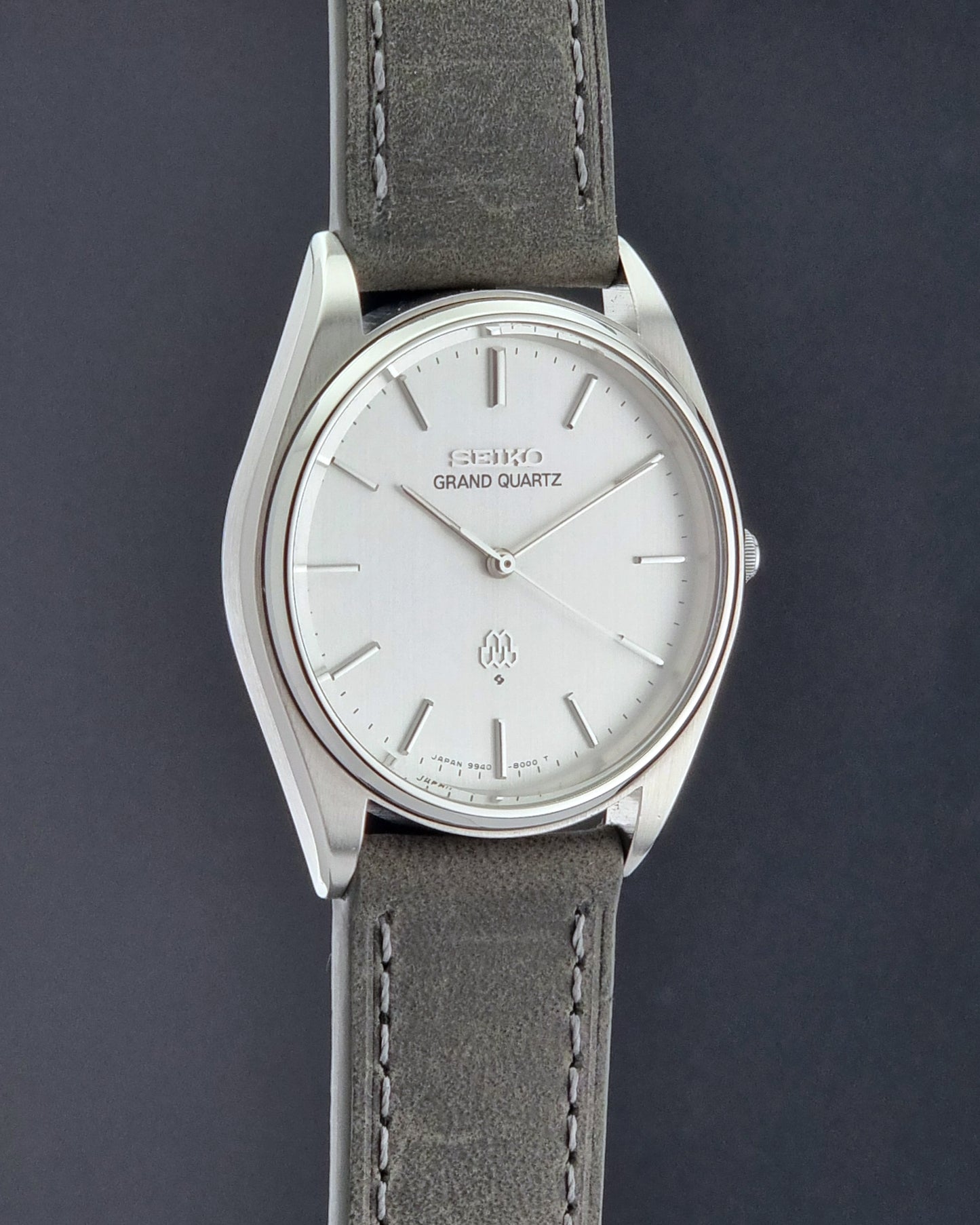 Vintage Seiko Grand Quartz 9940-8000 Watch with gray leather strap and white dial on a dark background side profile view