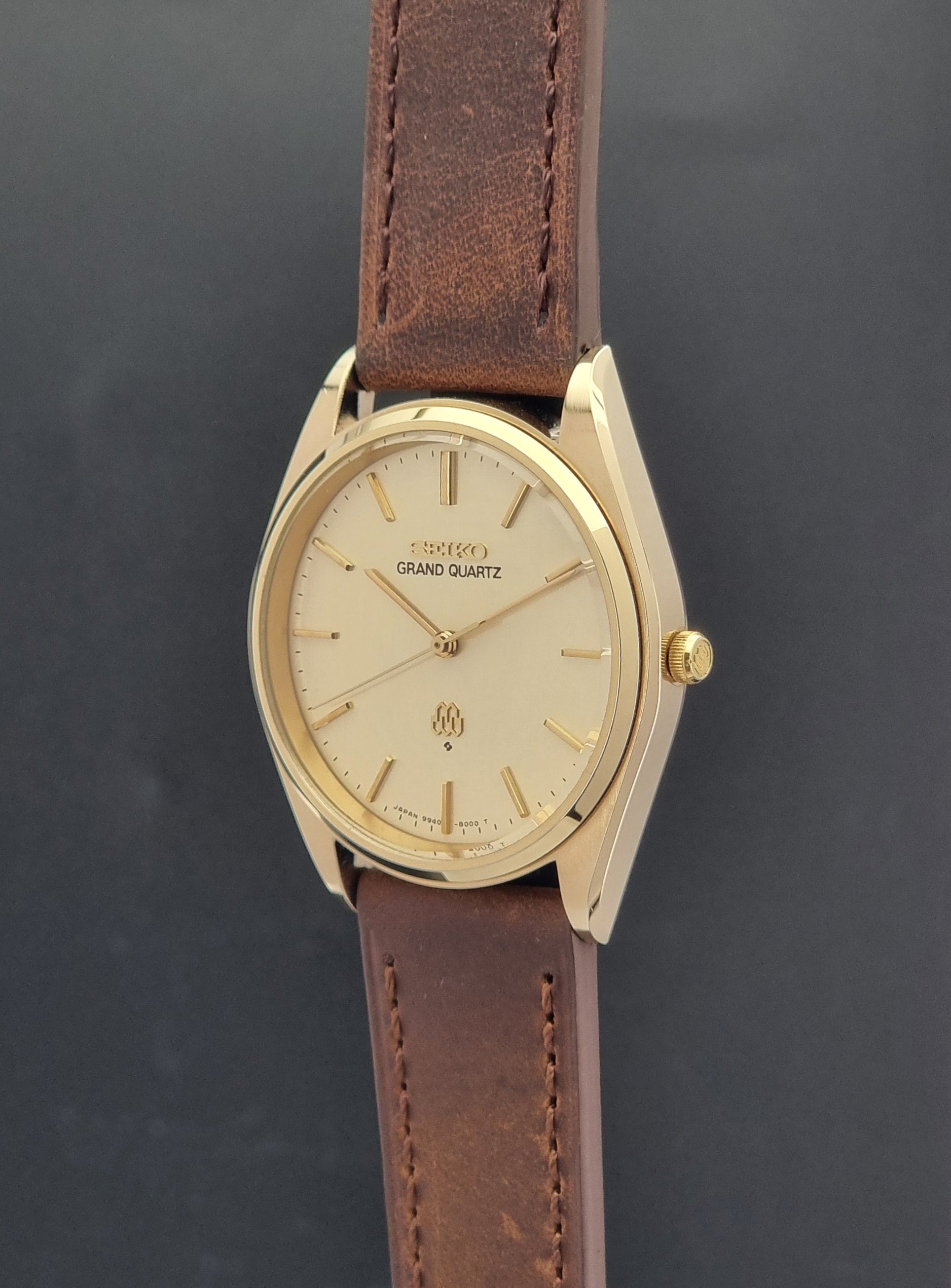 Vintage Seiko Grand Quartz watch 9940-8010 with brown leather strap on a dark textured background crown profile view
