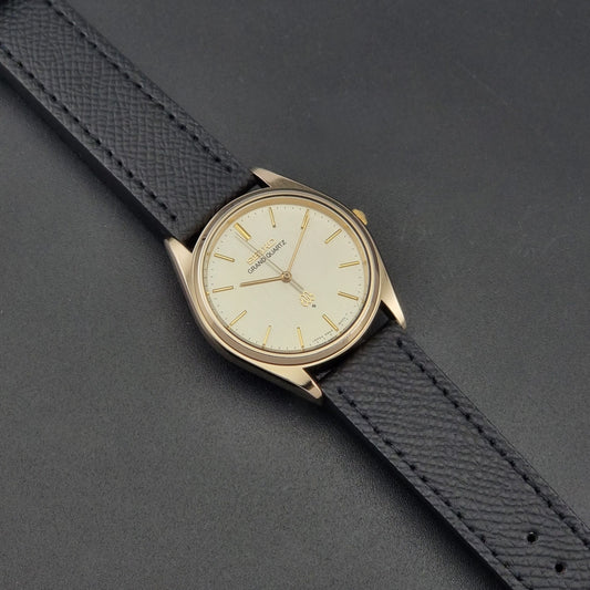 Vintage Seiko Grand Quartz 9940-8010  watch with gold case and black strap on a dark gray background front