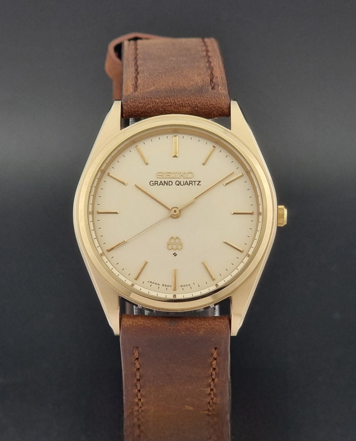 Vintage Seiko Grand Quartz watch 9940-8010 with brown leather strap on a dark textured background close dial view
