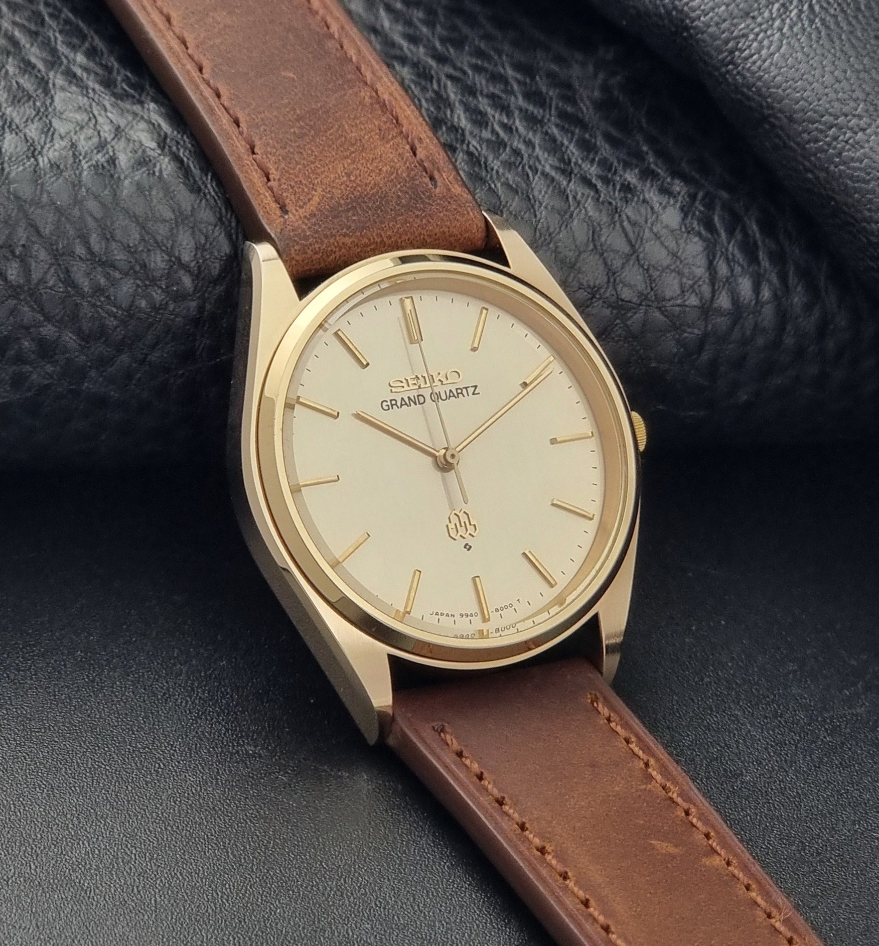 Vintage Seiko Grand Quartz watch 9940-8010 with brown leather strap on a dark textured background side view