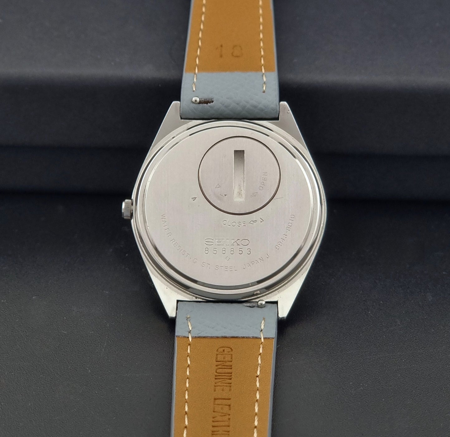 Vintage Seiko Grand Quartz 9943-8010 with a light grey strap on a dark background case back view