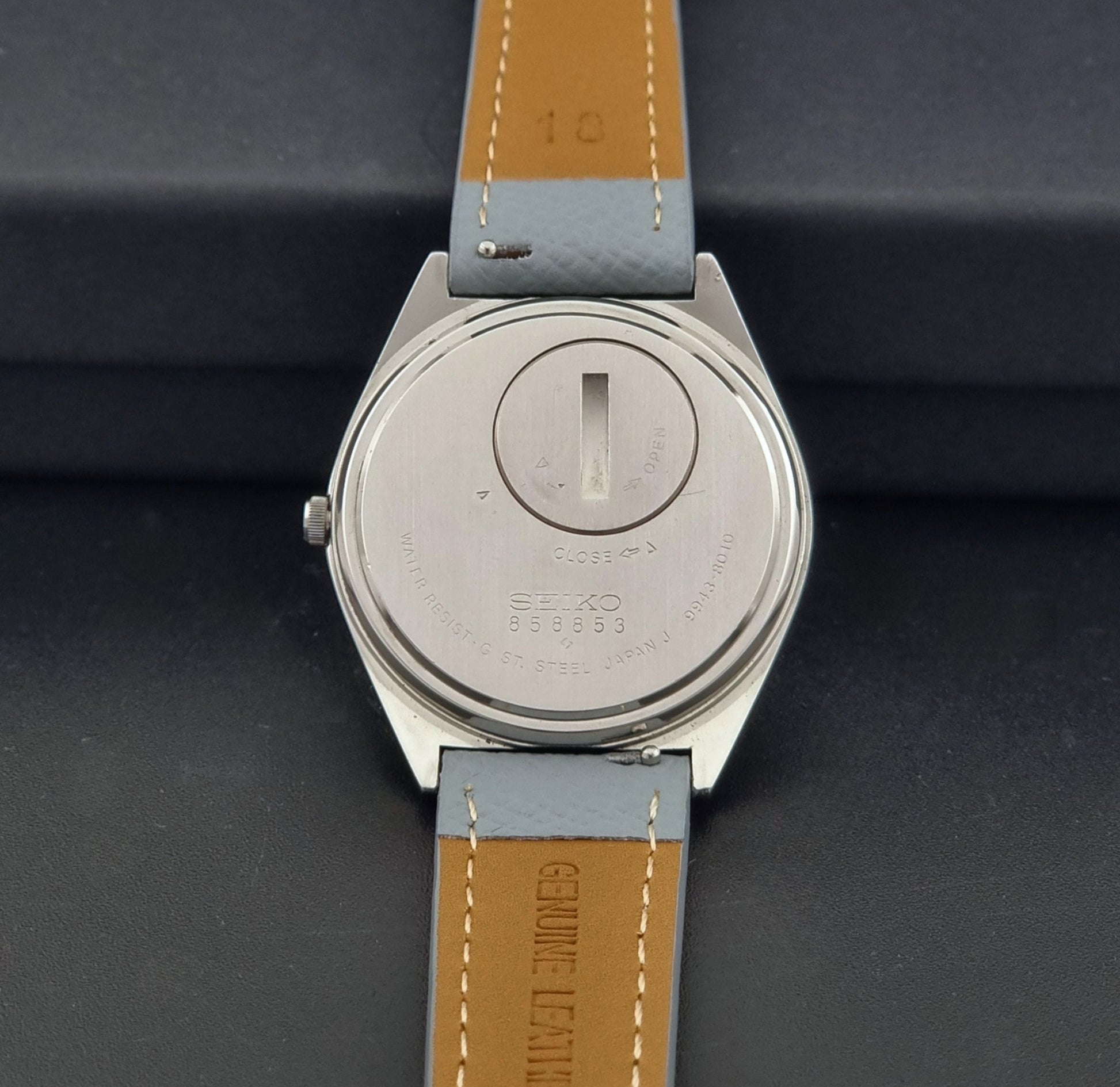 Vintage Seiko Grand Quartz 9943-8010 with a light grey strap on a dark background case back view