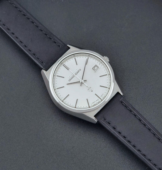 Vintage Seiko Grand Quartz watch 4842-8110 with a silver case and black leather strap on a dark gray background dial 