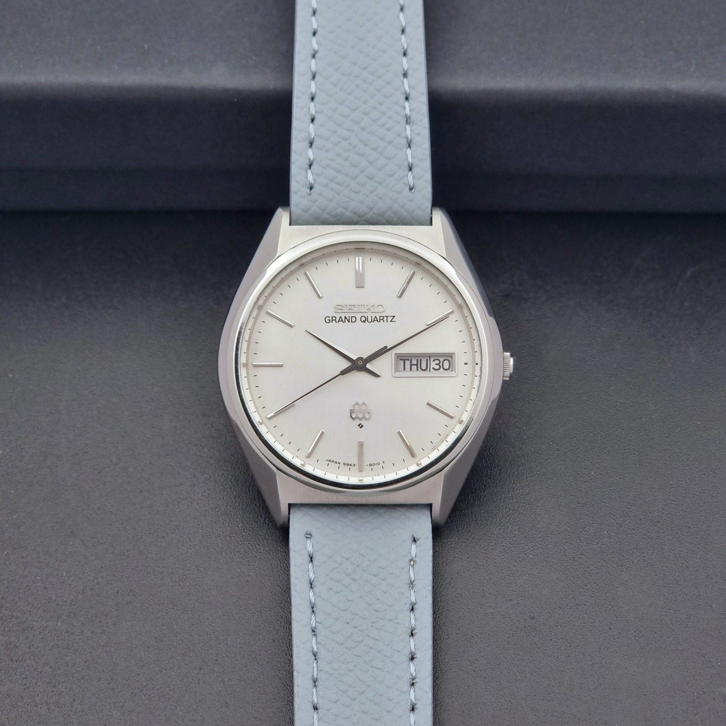 Vintage Seiko Grand Quartz 9943-8010 with a light grey strap on a dark background dial view