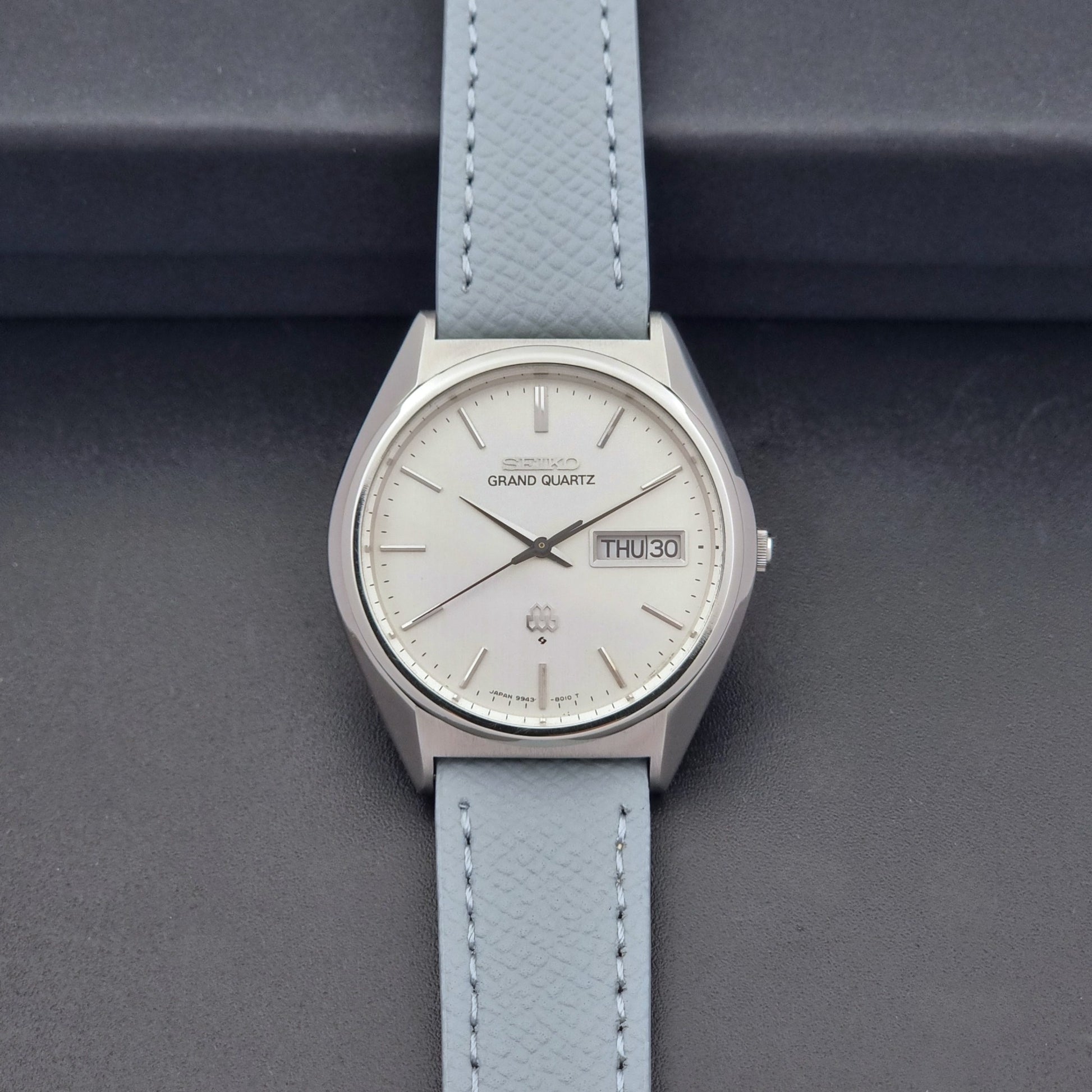Vintage Seiko Grand Quartz 9943-8010 with a light grey strap on a dark background dial view