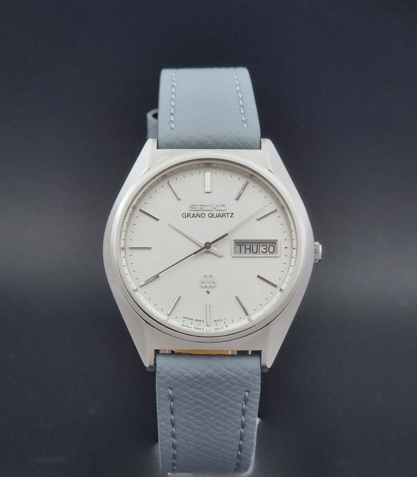 Vintage Seiko Grand Quartz 9943-8010 with a light grey strap on a dark background close dial view
