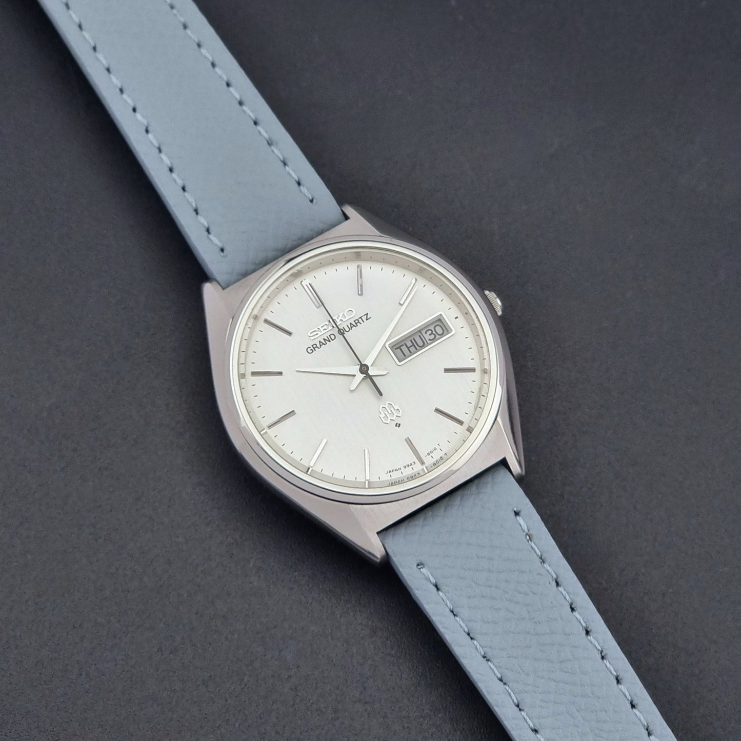 Vintage Seiko Grand Quartz 9943-8010 with a light grey strap on a dark background close up dial view
