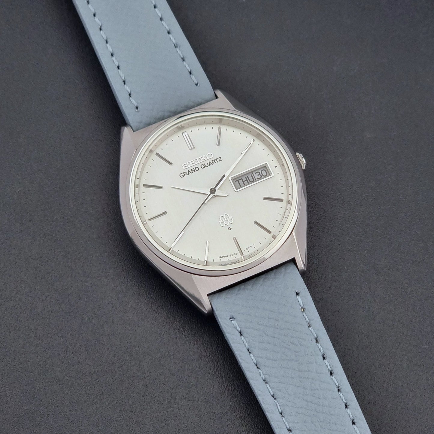 Vintage Seiko Grand Quartz 9943-8010 with a light grey strap on a dark background front view
