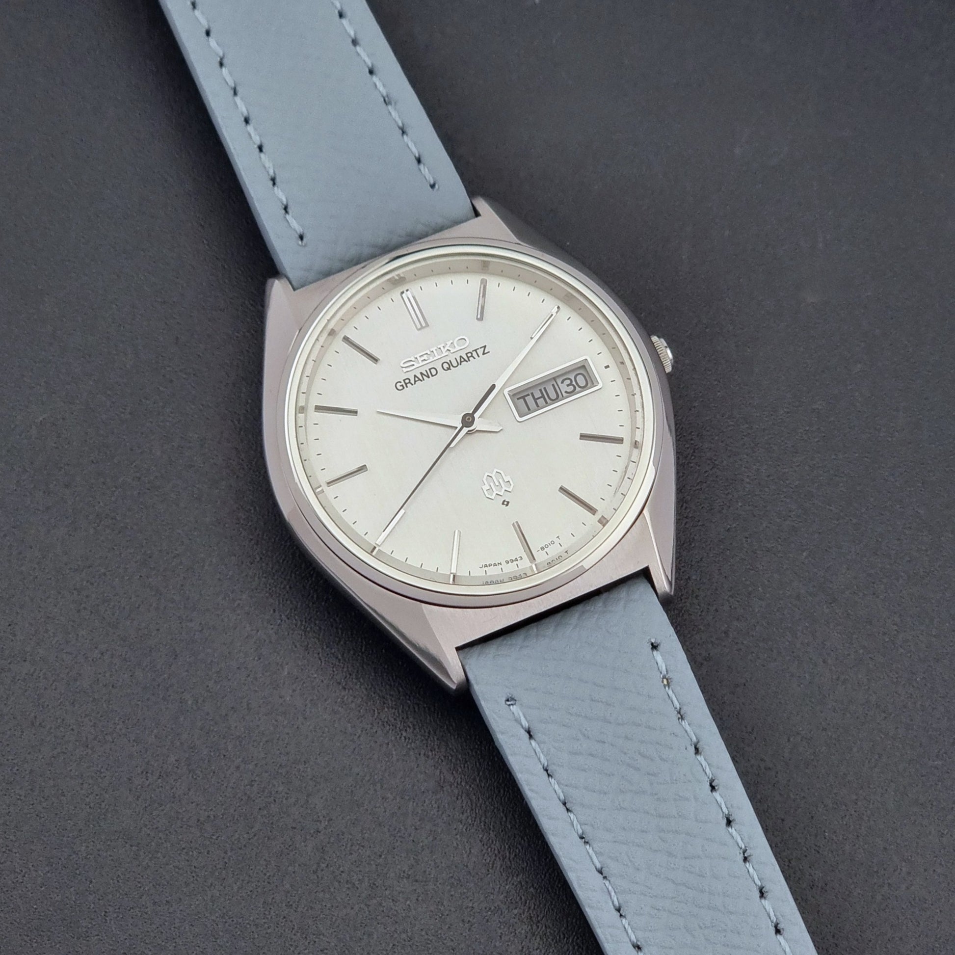 Vintage Seiko Grand Quartz 9943-8010 with a light grey strap on a dark background front view