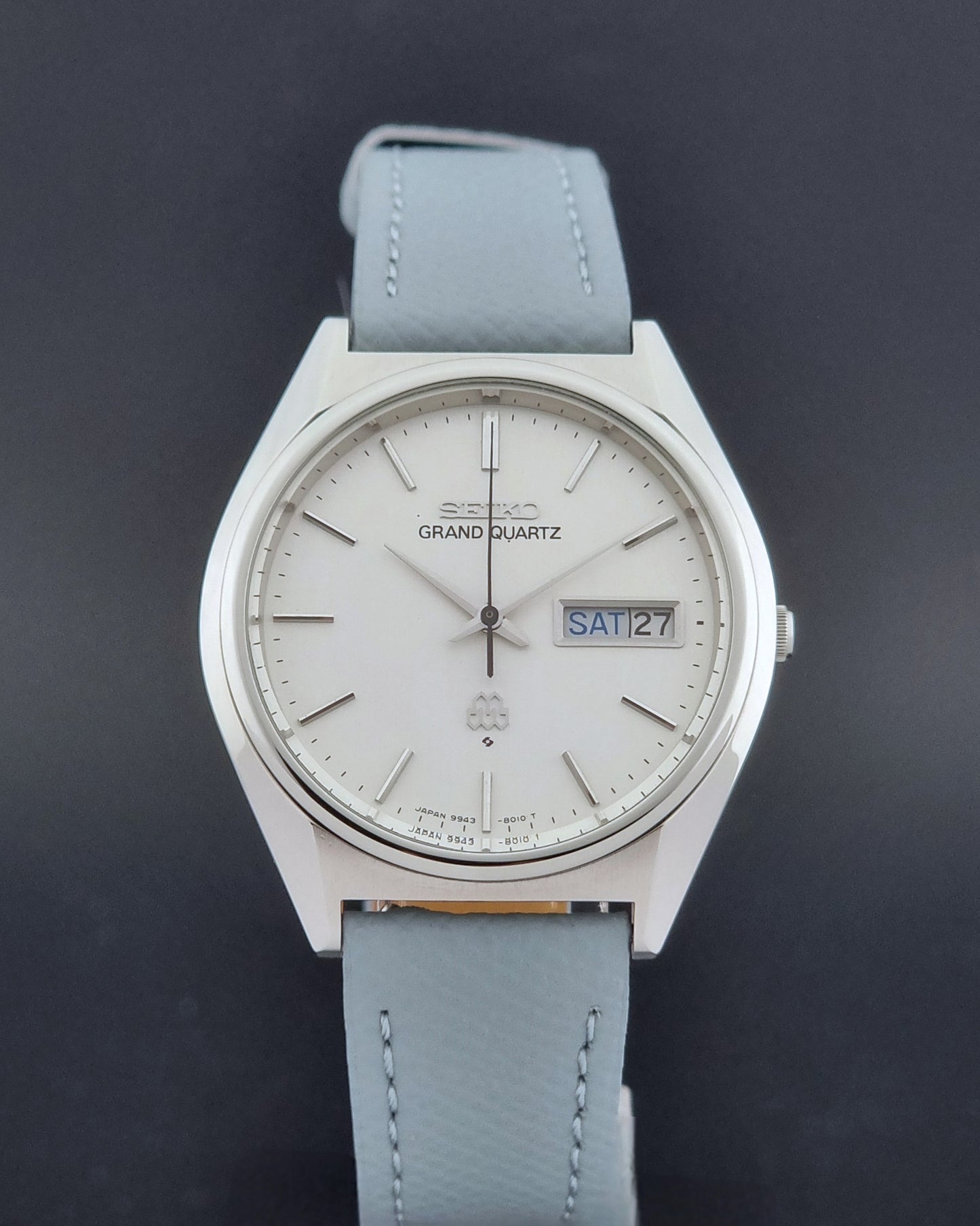 Vintage Seiko Grand Quartz Wristwatch 9943-8010 with grey strap on a dark gray background close dial view