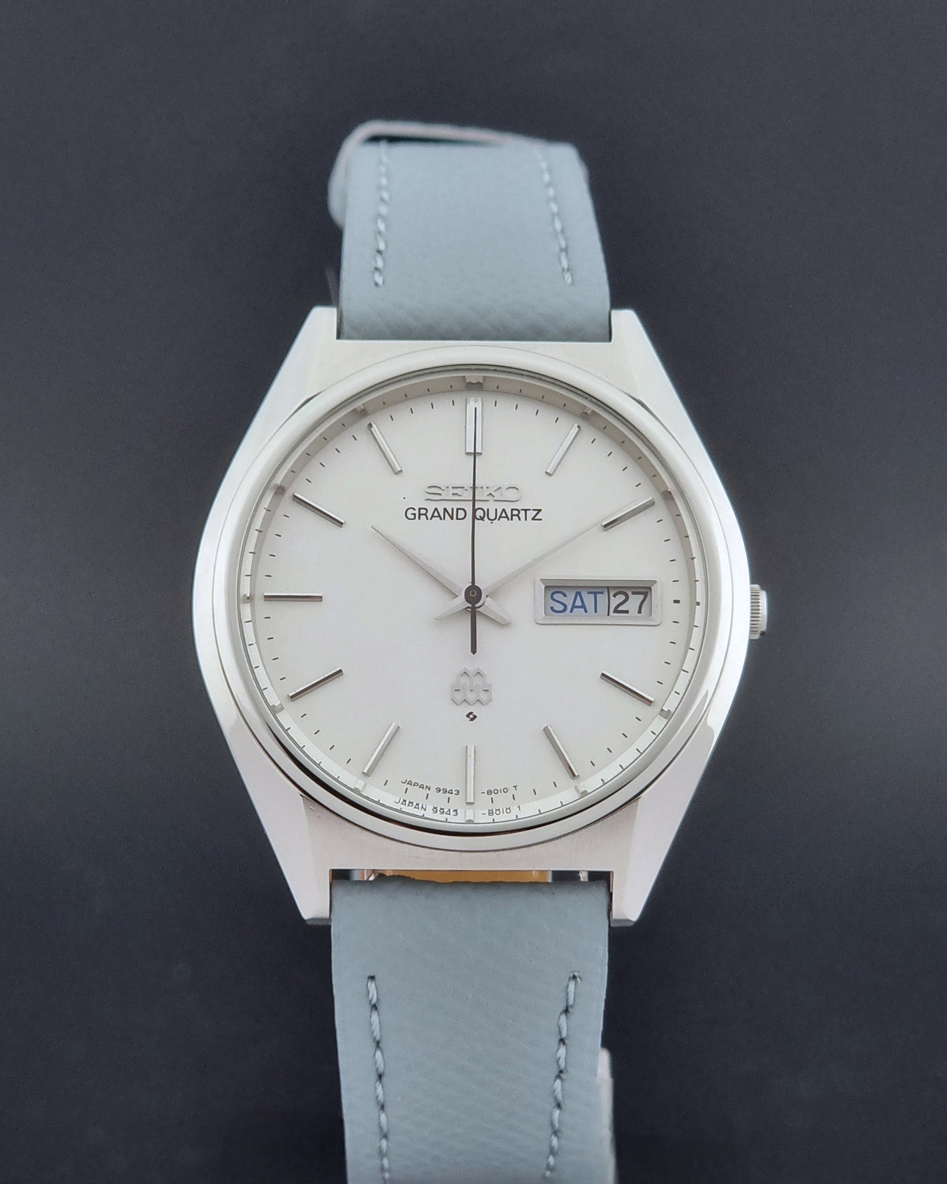 Vintage Seiko Grand Quartz Wristwatch 9943-8010 with grey strap on a dark gray background close dial view