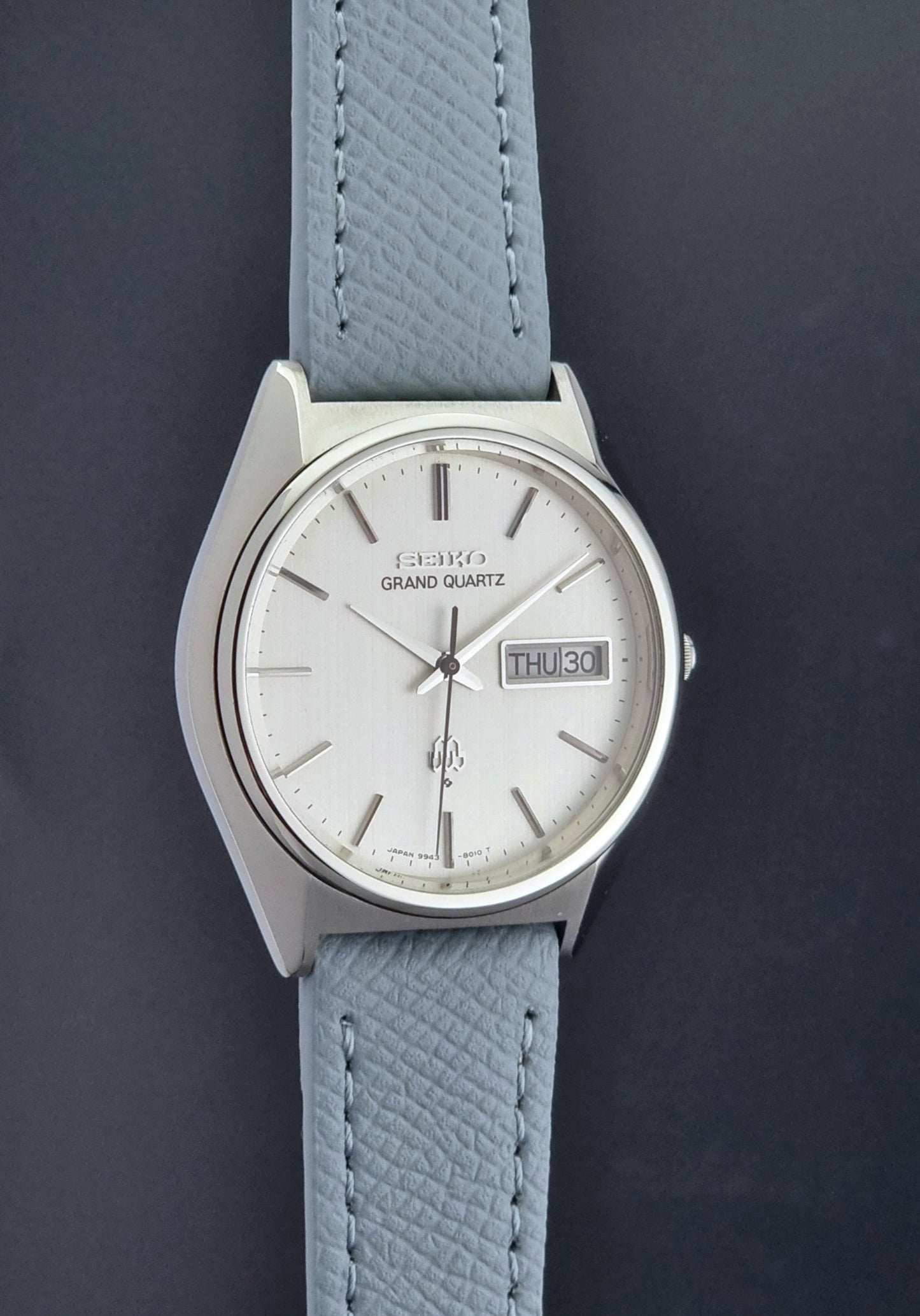 Vintage Seiko Grand Quartz 9943-8010 with a light grey strap on a dark background side profile view