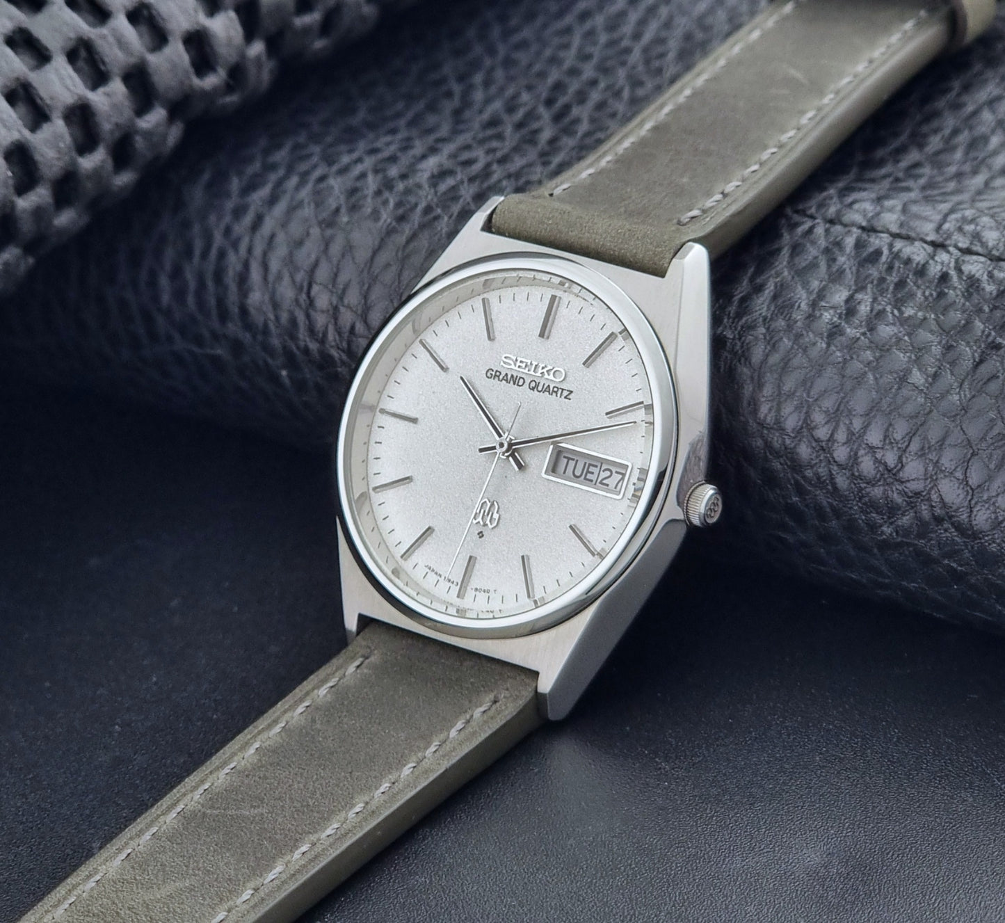 Vintage Seiko Grand Quartz watch 9943-8030 with gray leather strap on a dark gray background crown view