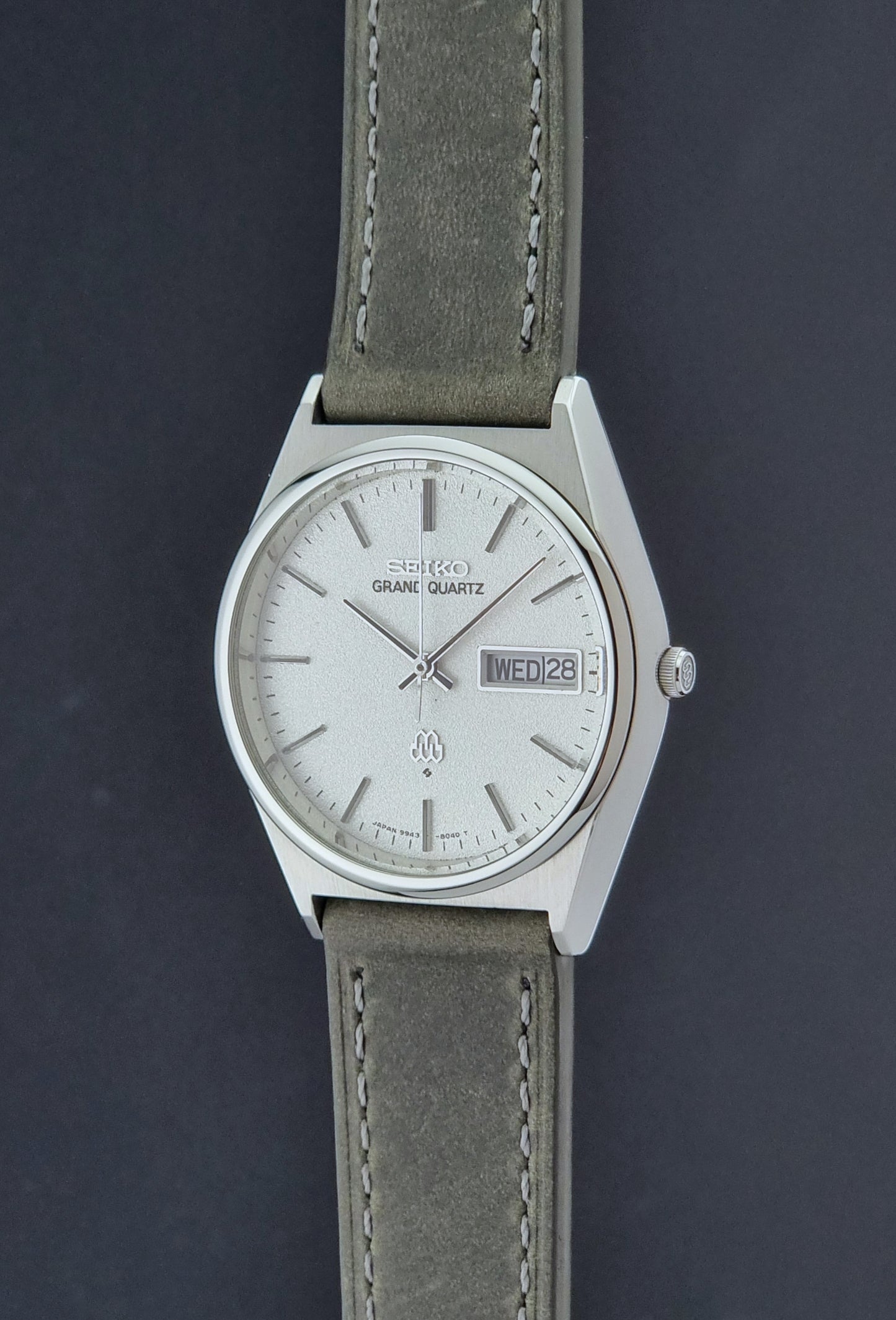 Vintage Seiko Grand Quartz watch 9943-8030 with gray leather strap on a dark gray background crown profile view