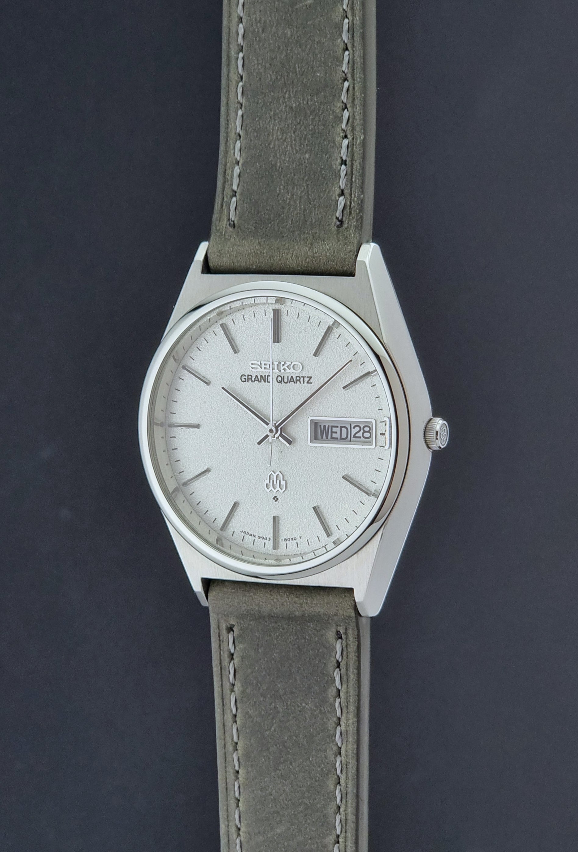 Vintage Seiko Grand Quartz watch 9943-8030 with gray leather strap on a dark gray background crown profile view