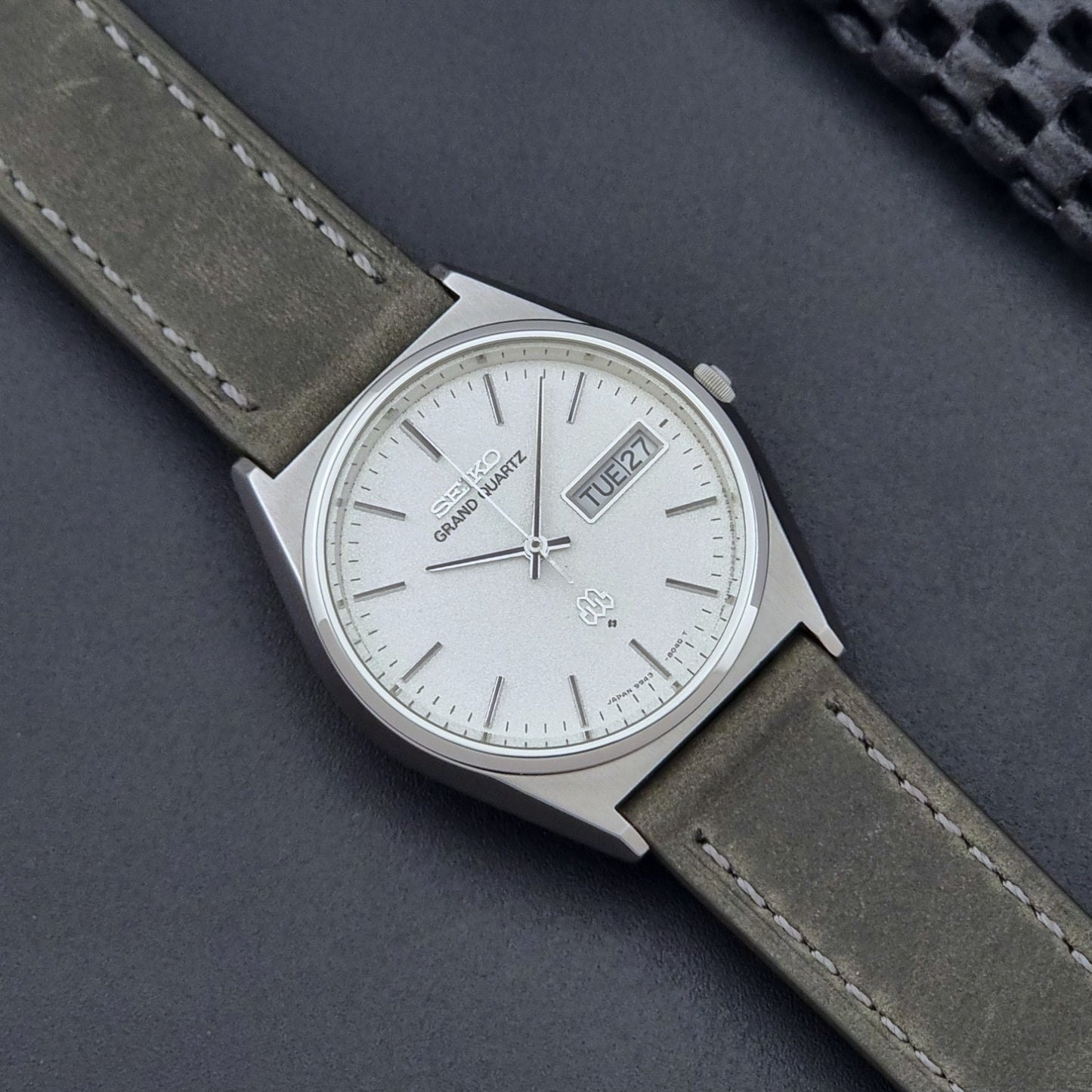 Vintage Seiko Grand Quartz watch 9943-8030 with gray leather strap on a dark gray background close up dial view