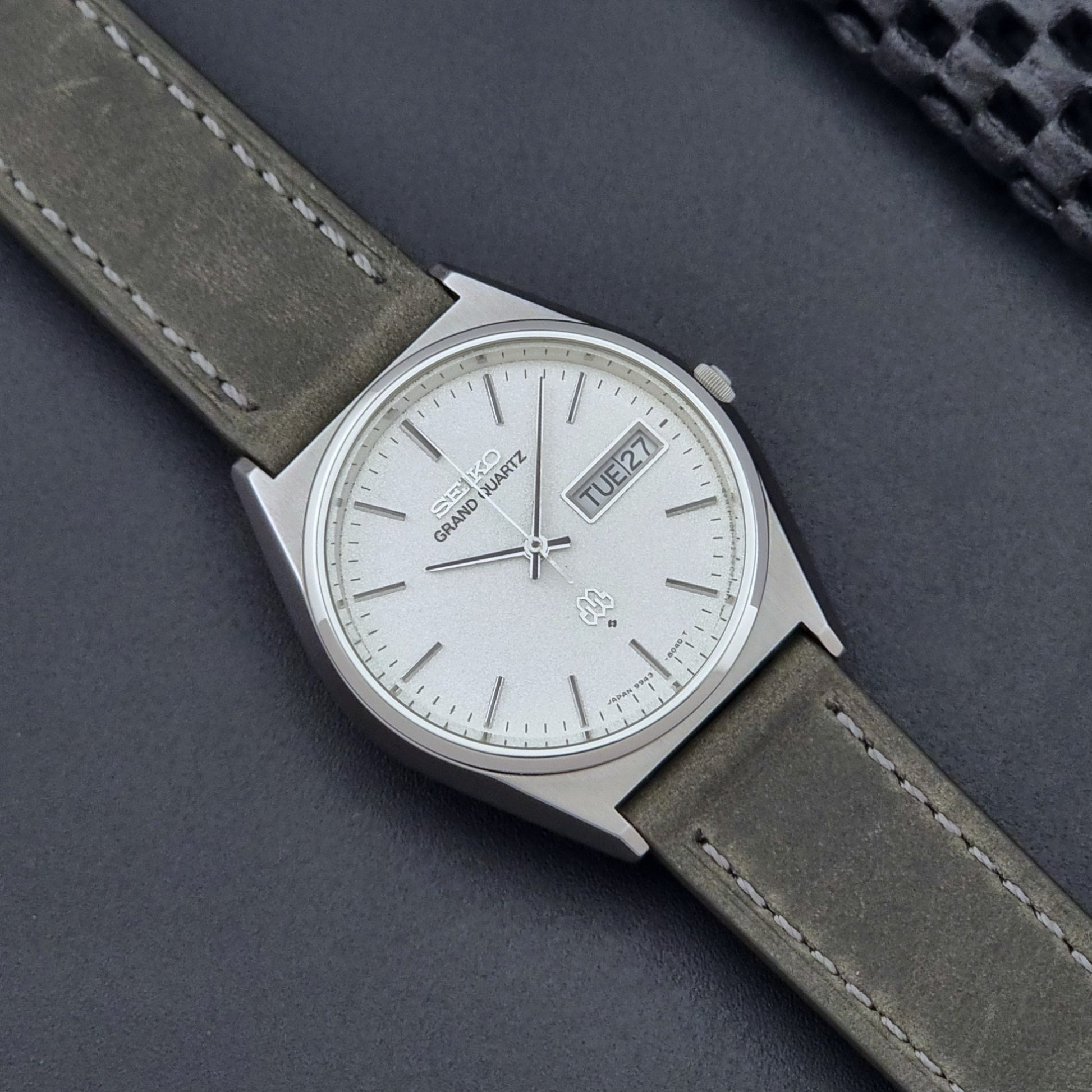 Vintage Seiko Grand Quartz watch 9943-8030 with gray leather strap on a dark gray background close up dial view