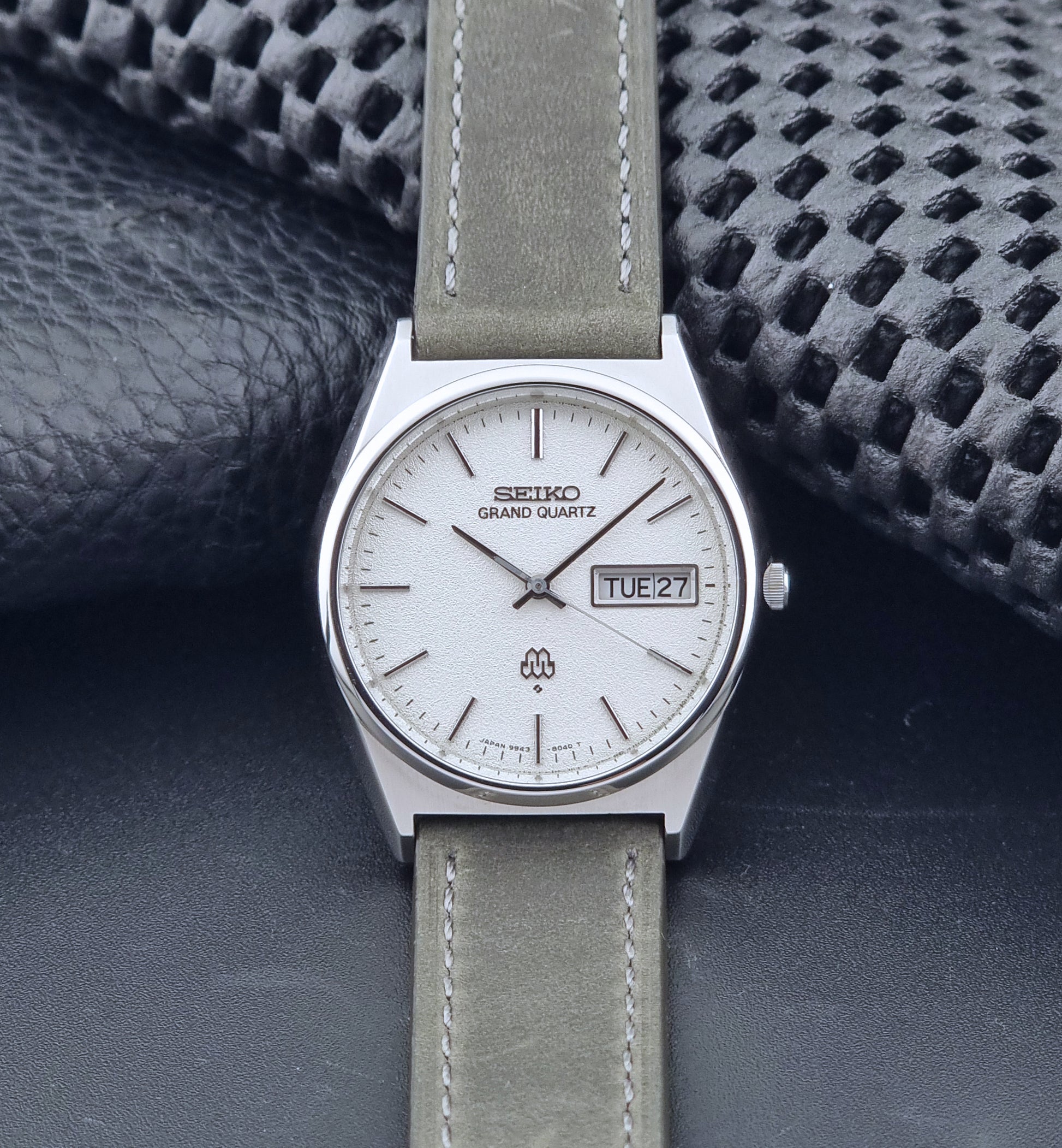 Vintage Seiko Grand Quartz watch 9943-8030 with gray leather strap on a dark gray background dial view