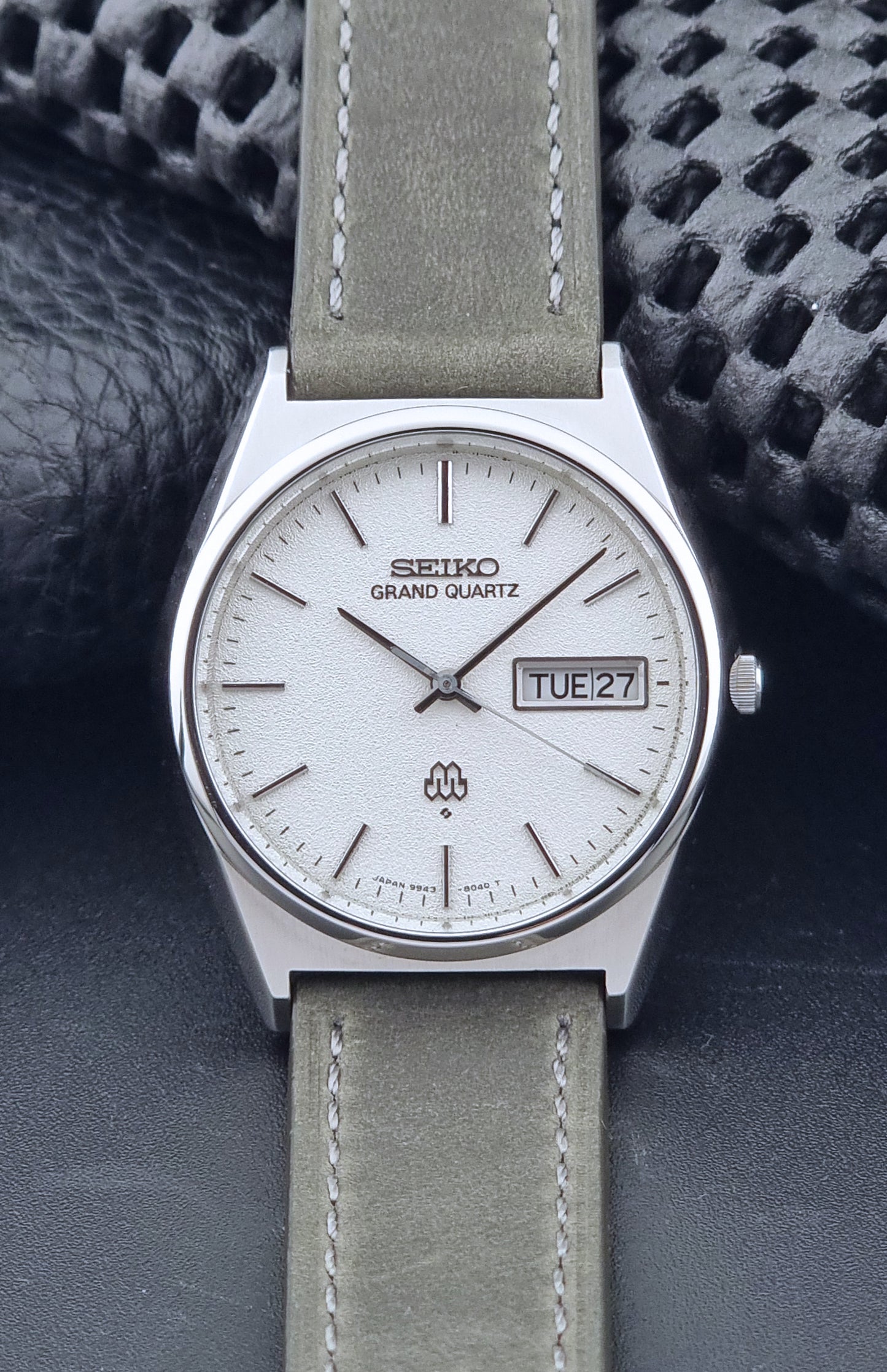 Vintage Seiko Grand Quartz watch 9943-8030 with gray leather strap on a dark gray background front view