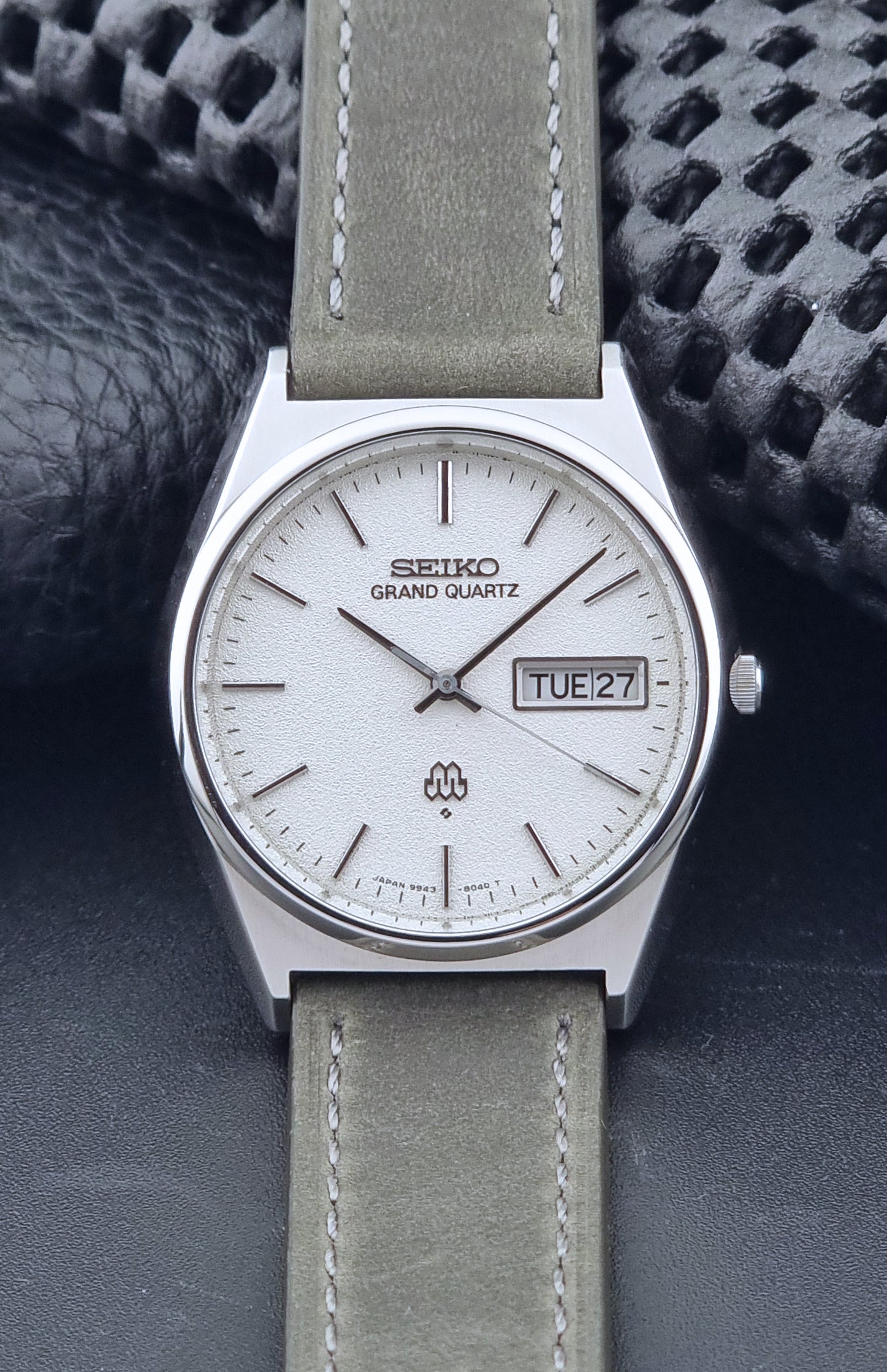 Vintage Seiko Grand Quartz watch 9943-8030 with gray leather strap on a dark gray background front view