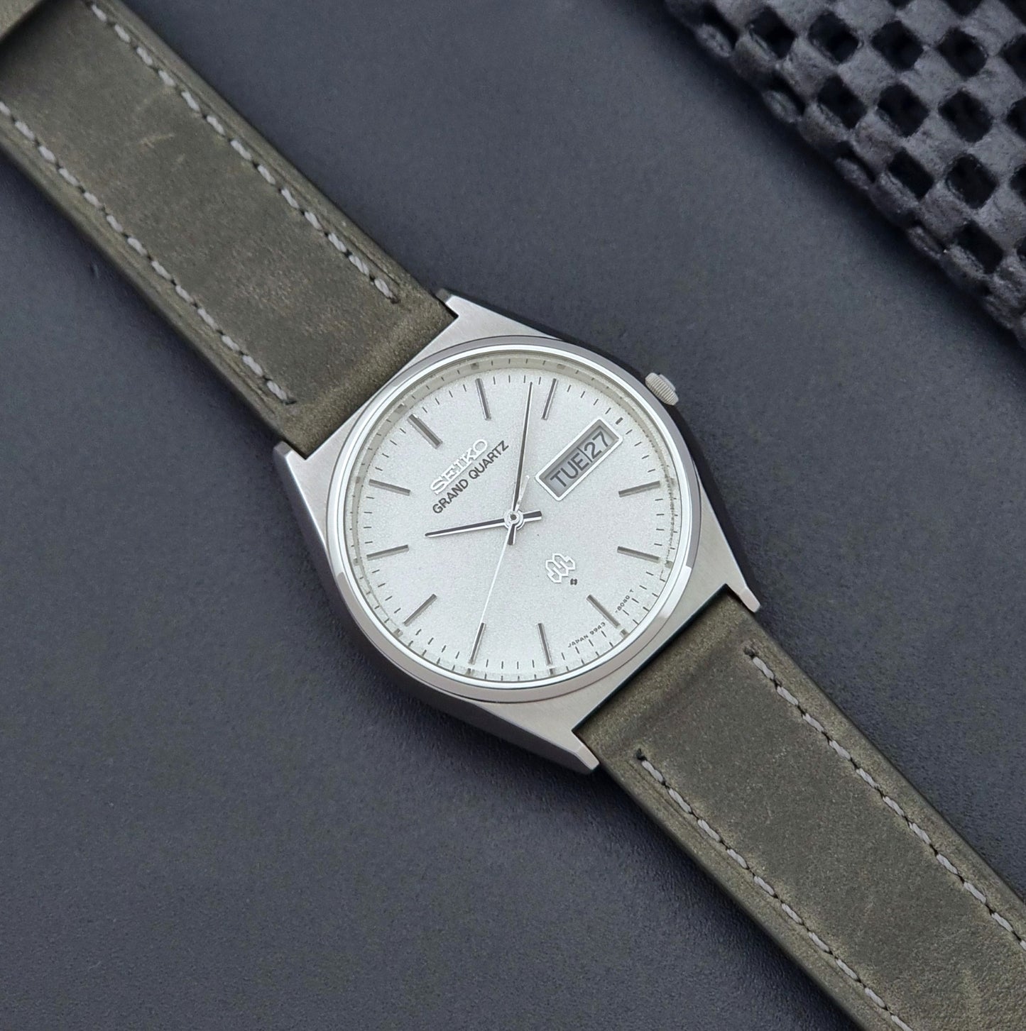 Vintage Seiko Grand Quartz watch 9943-8030 with gray leather strap on a dark gray background dial