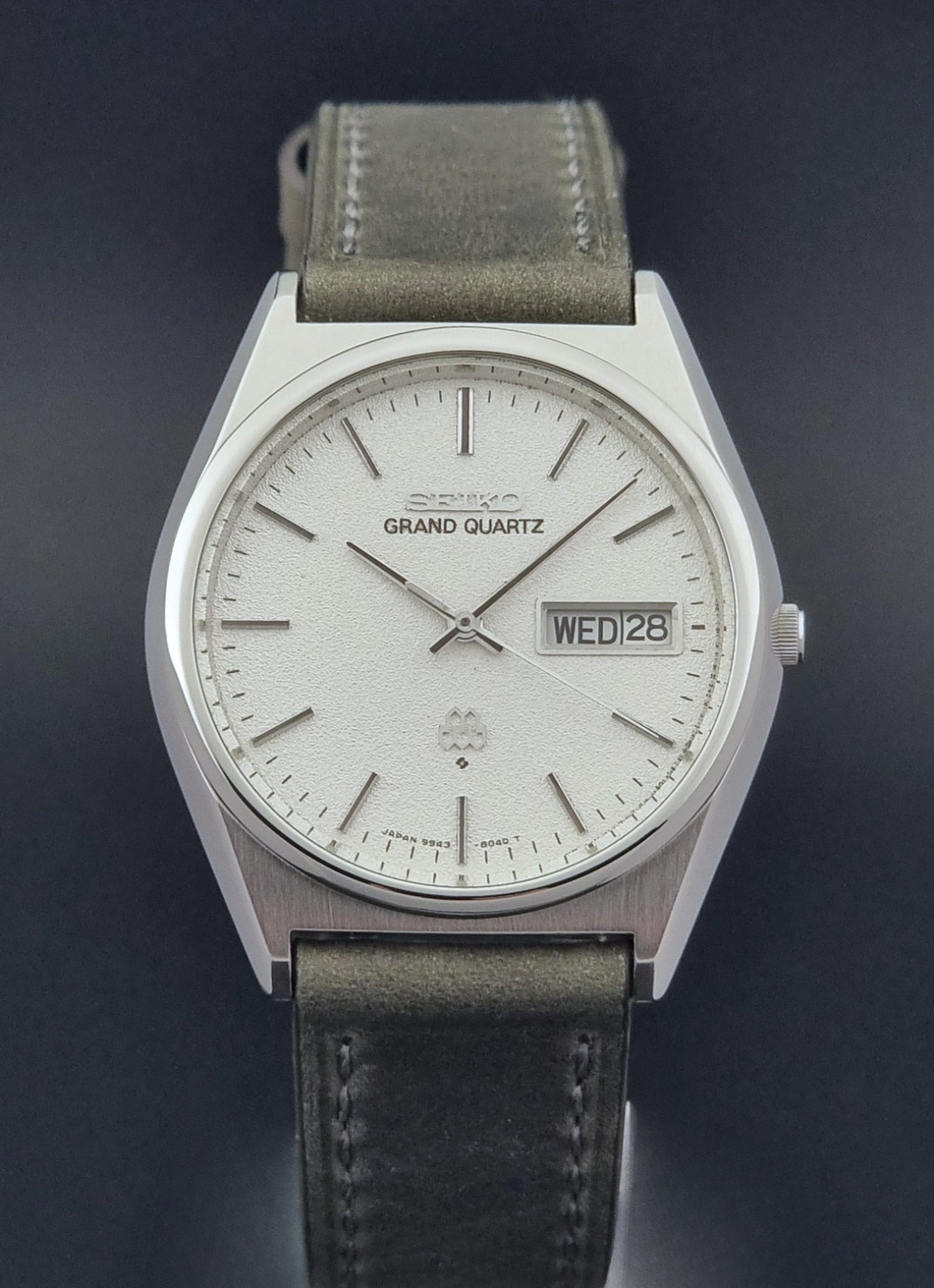 Vintage Seiko Grand Quartz watch 9943-8030 with gray leather strap on a dark gray background close dial view