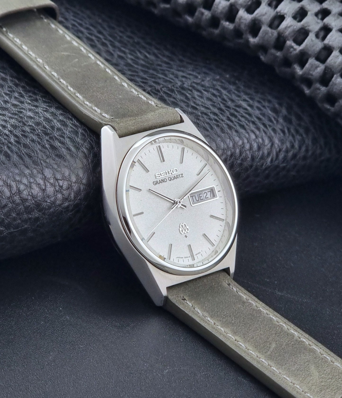 Vintage Seiko Grand Quartz watch 9943-8030 with gray leather strap on a dark gray background side view