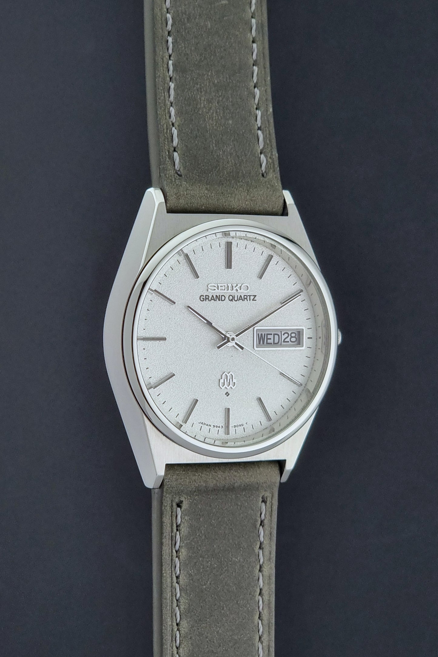 Vintage Seiko Grand Quartz watch 9943-8030 with gray leather strap on a dark gray background side profile view